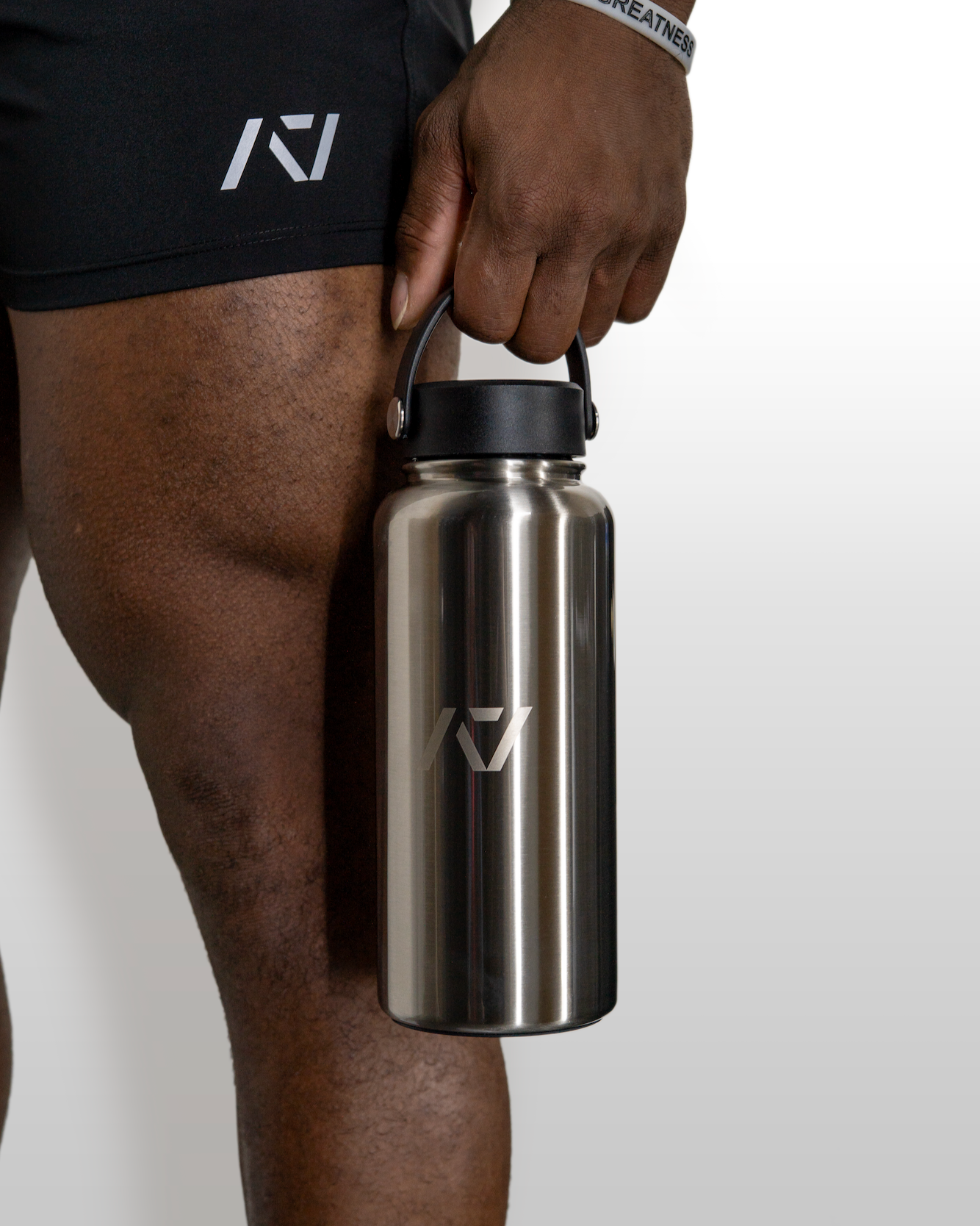 Person holding a stainless steel water bottle with a brand logo on a plain background