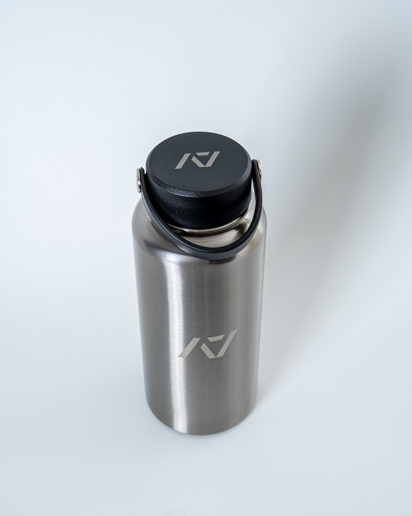 Stainless steel water bottle with black lid on a white background