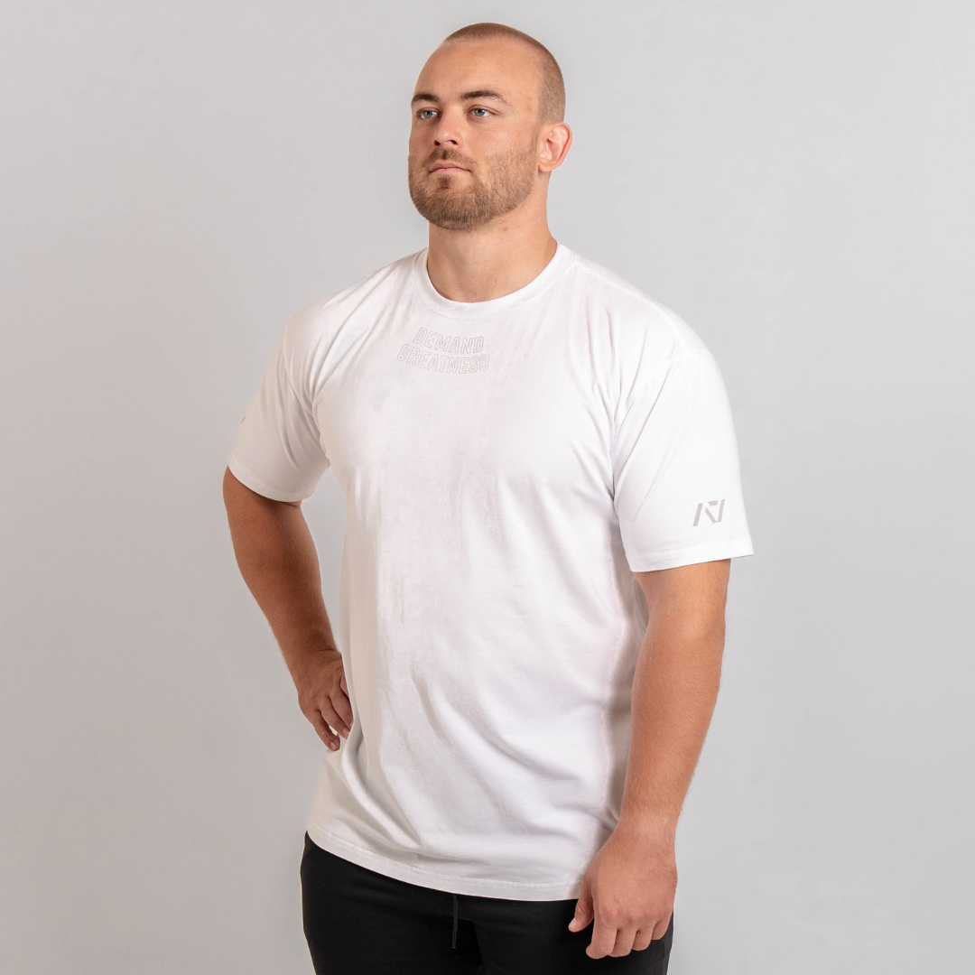 A man wearing a white t-shirt with the text 'Demand Greatness' on the upper chest and the A7 logo on the upper back and sleeves.