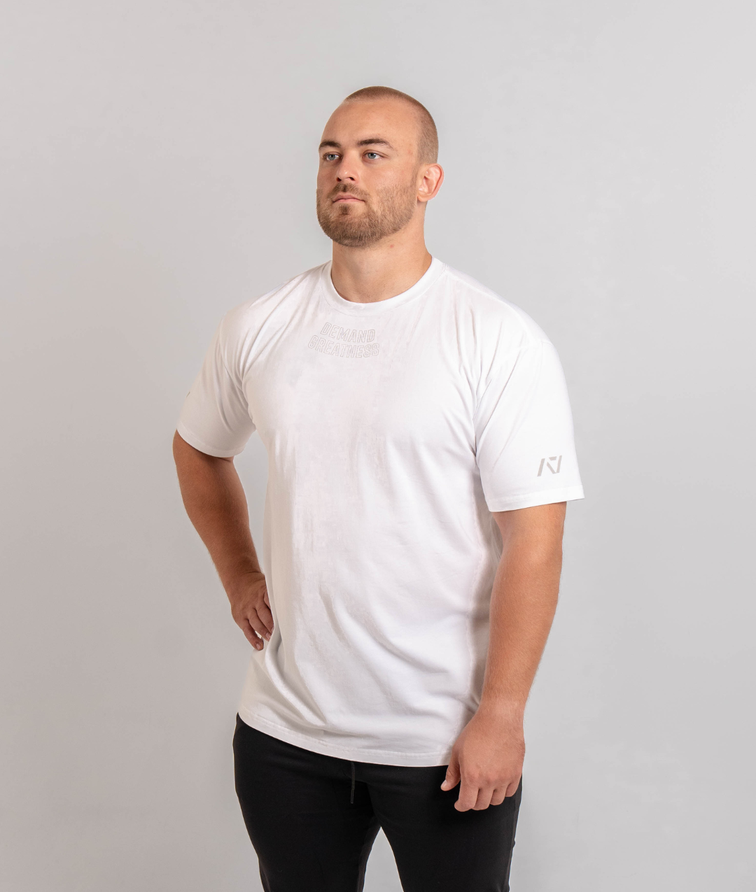 A man wearing a white t-shirt with the text 'Demand Greatness' on the upper chest and the A7 logo on the upper back and sleeves.