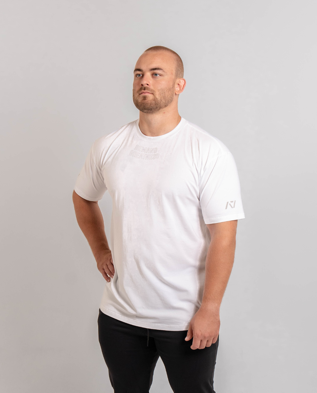 A man wearing a white t-shirt with the text 'Demand Greatness' on the upper chest and the A7 logo on the upper back and sleeves.