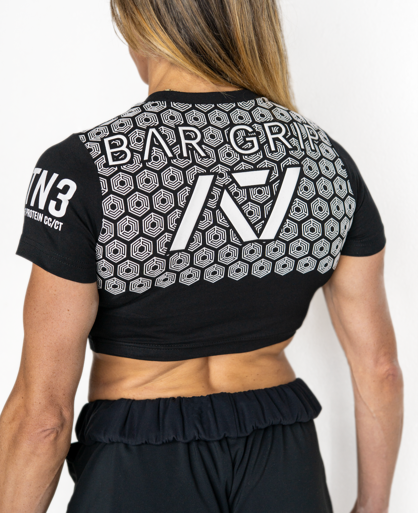 Person wearing a black sports outfit with bar grip and branding on a white background