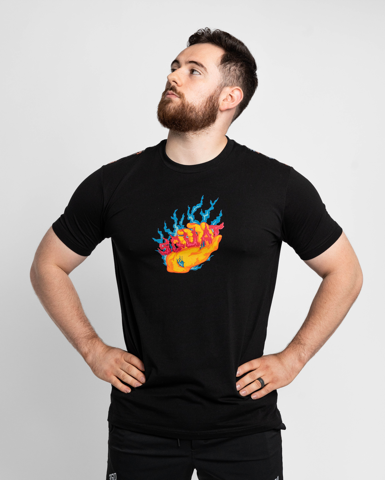 Man wearing a black t-shirt with a colorful graphic design on a plain background