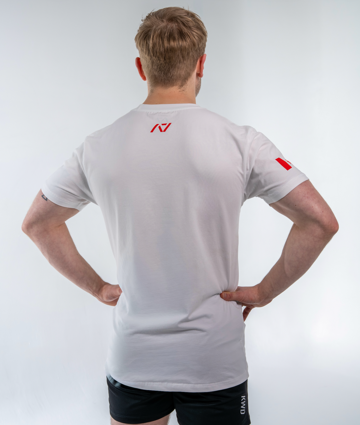 Person wearing a white shirt with a red logo on a light gray background