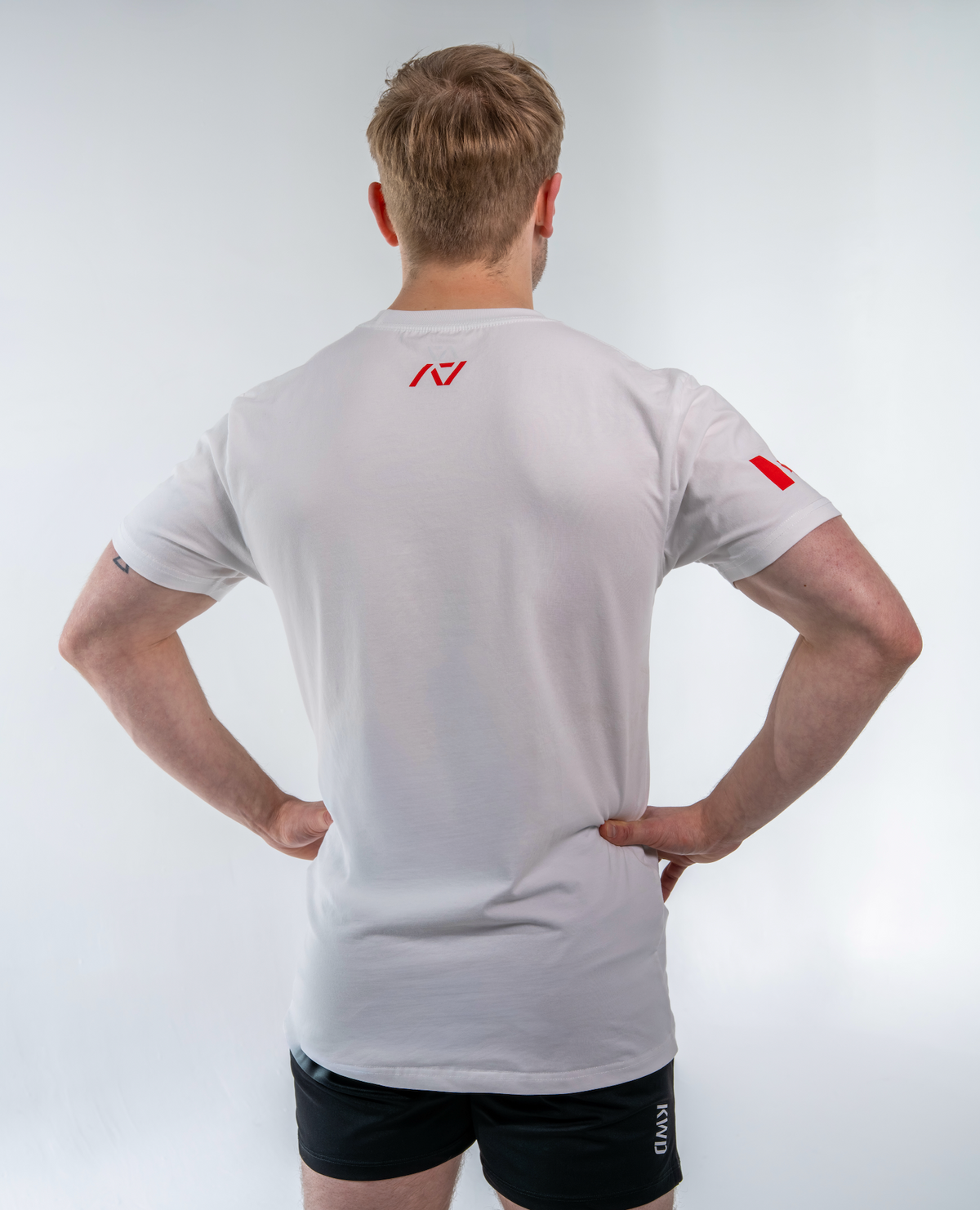 Person wearing a white shirt with a red logo on a light gray background