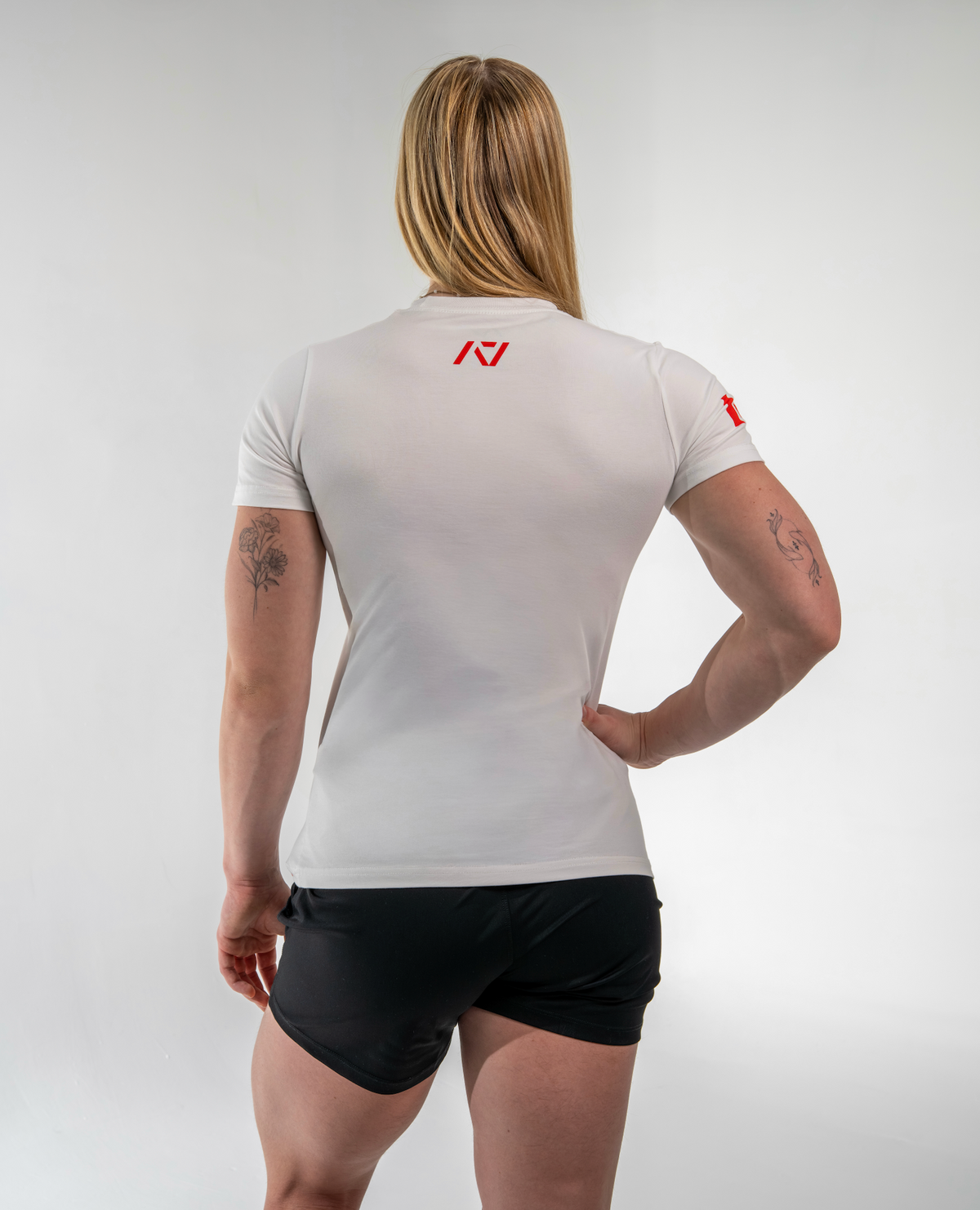Person wearing a white athletic shirt with a logo on the back, standing against a plain background