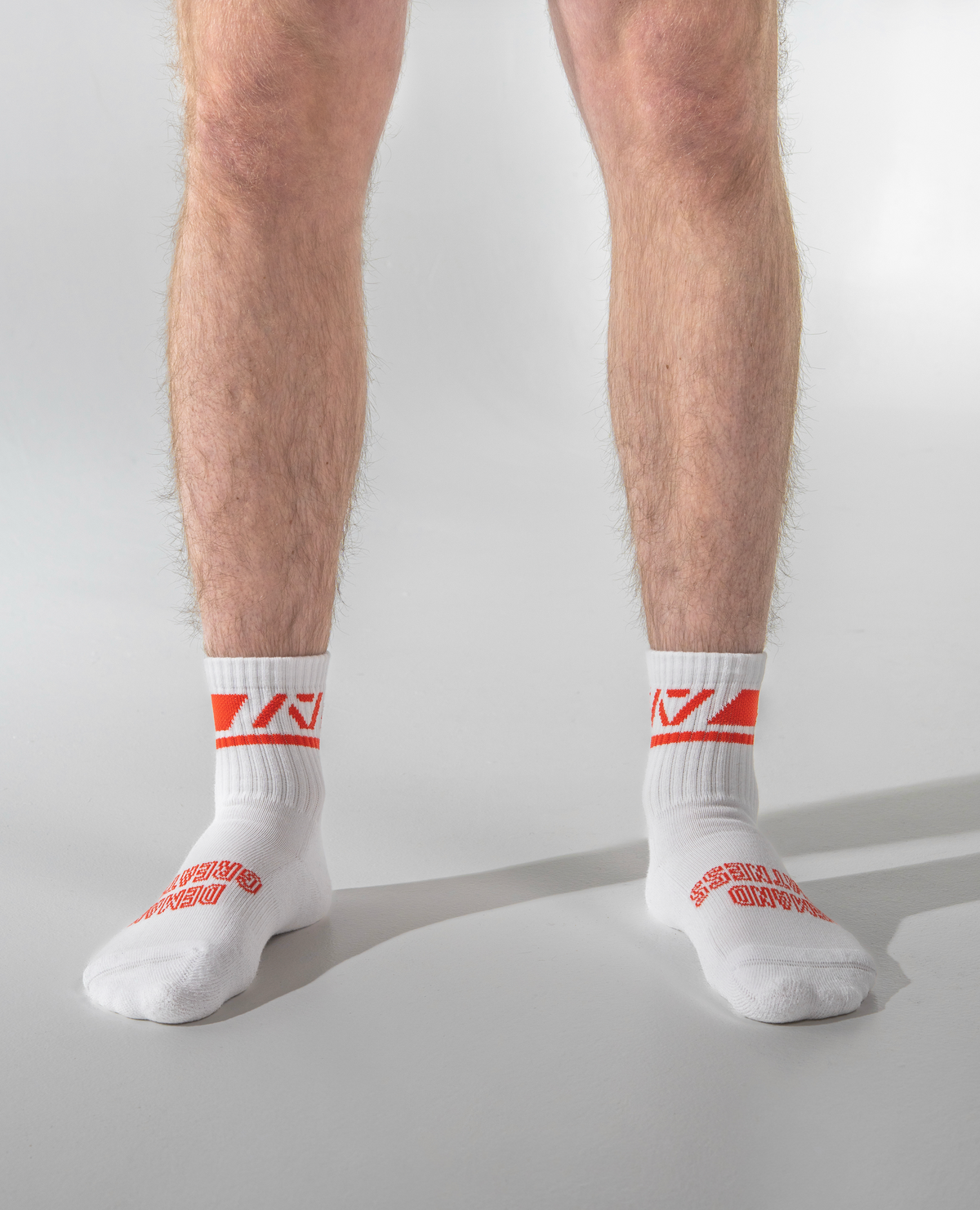 White socks with red logo worn by a person on a light gray background