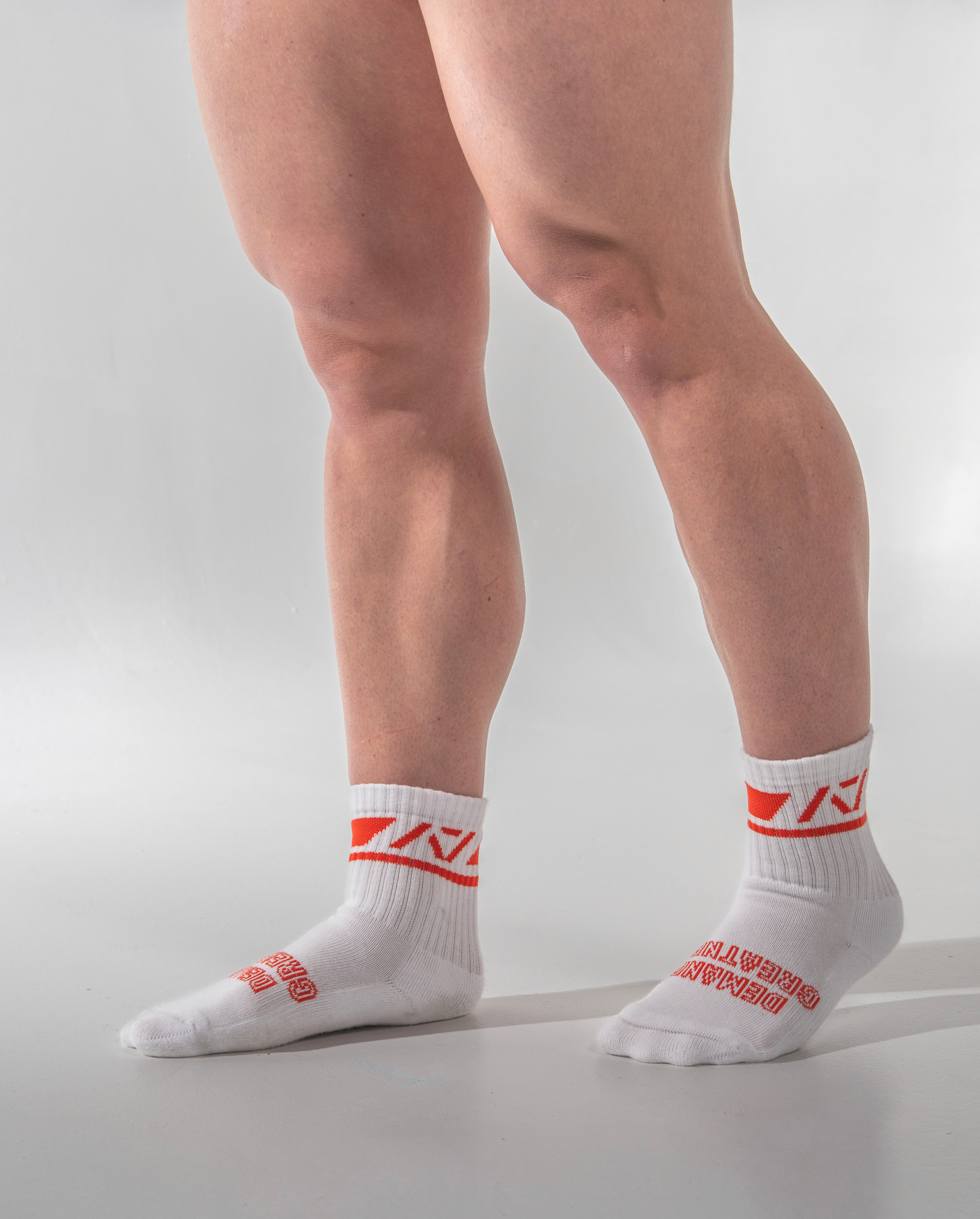 White socks with red logo worn by a person on a light gray background