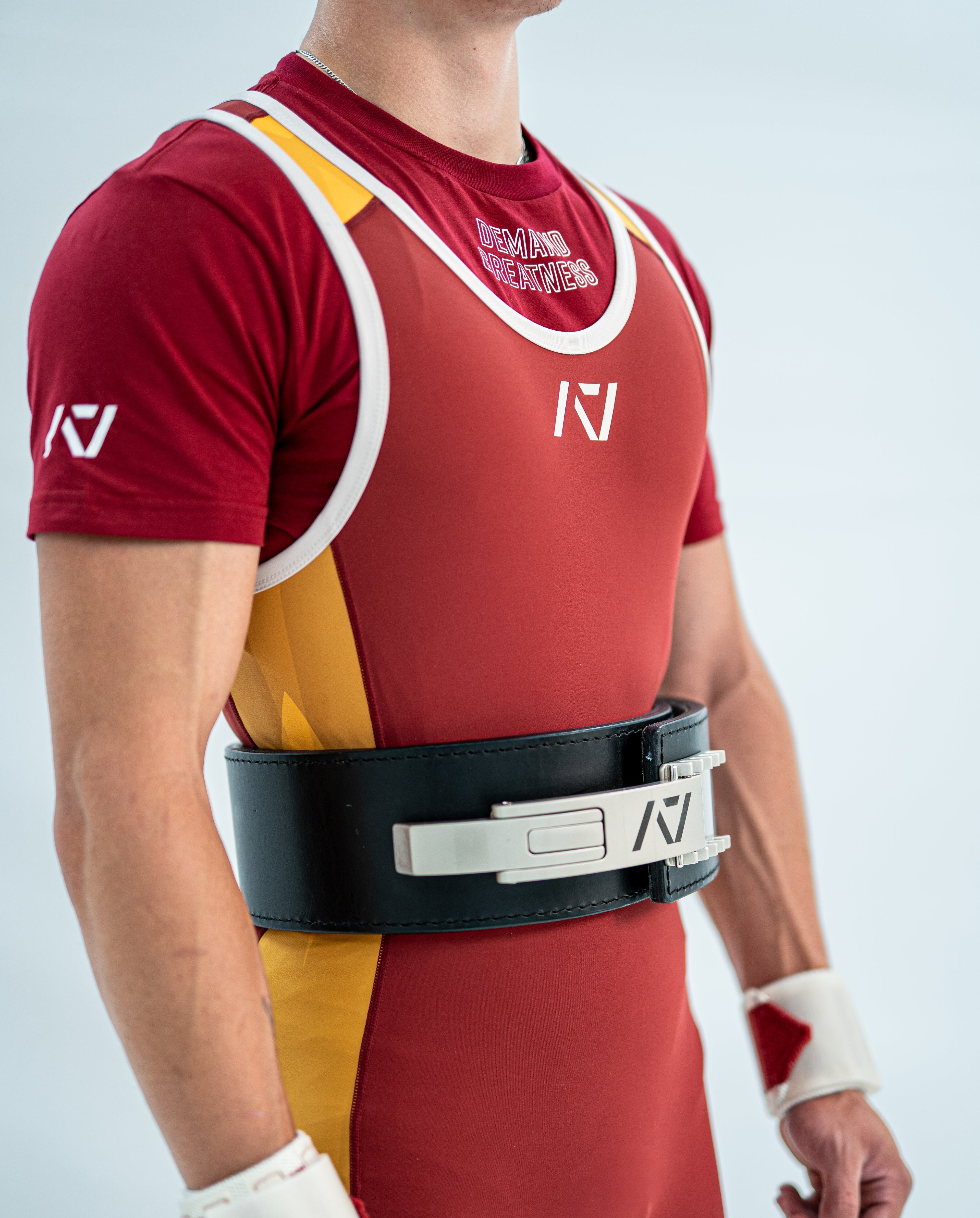 Male Model wearing a red and yellow powerlifting singlet with white accents on a light gray background