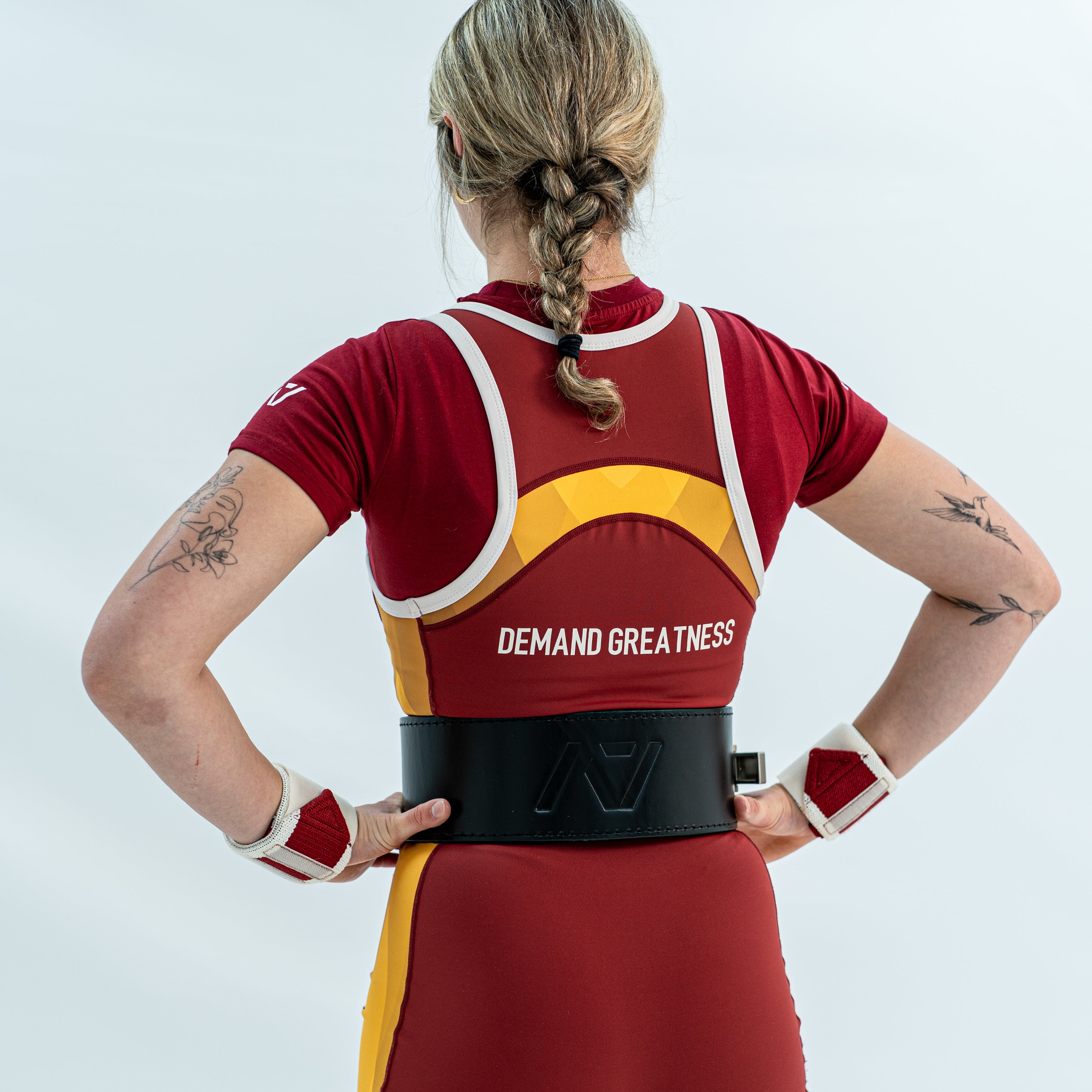 Person wearing a red and yellow rausch singlet with 'Demand Greatness' text on a white background