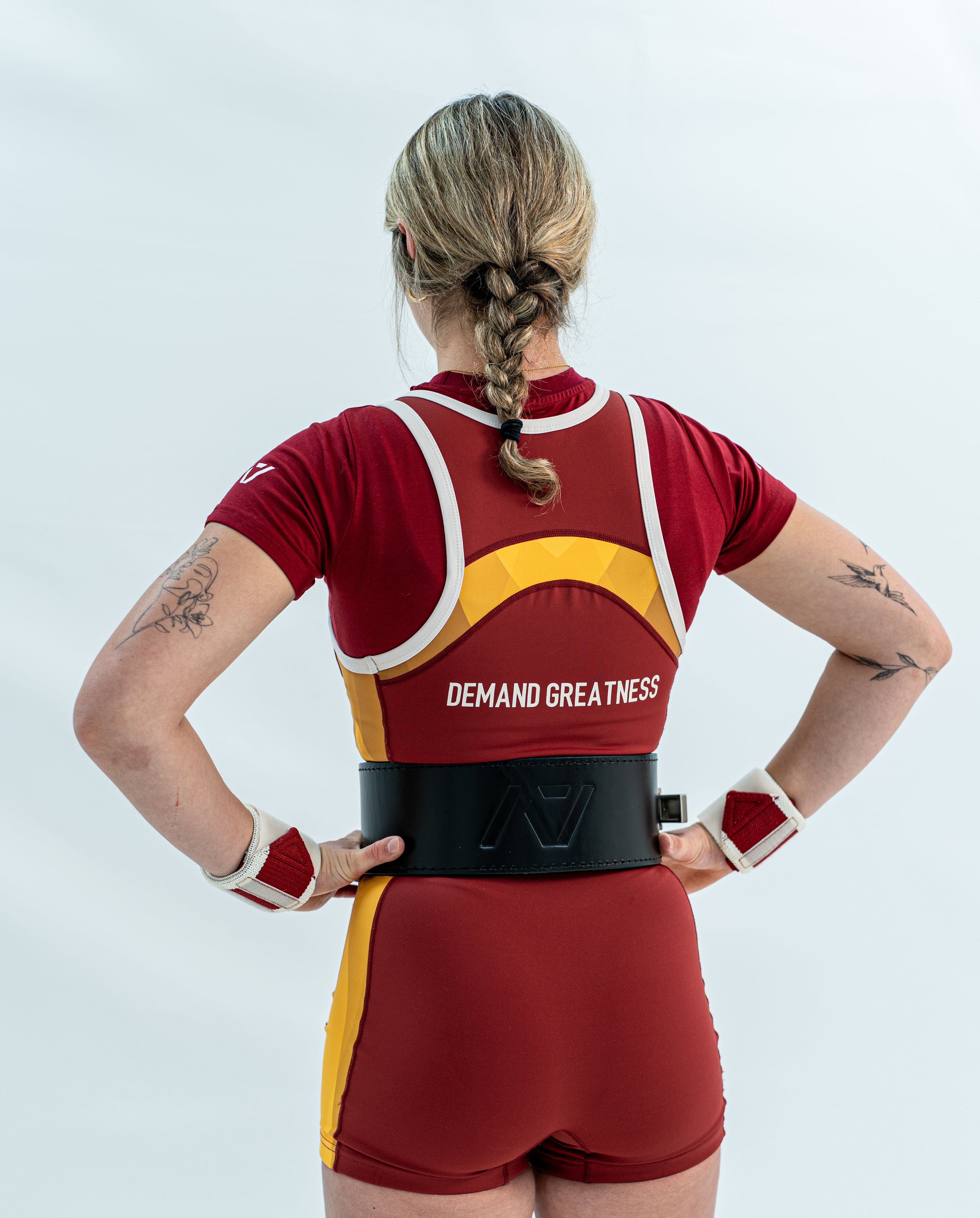 Person wearing a red and yellow rausch singlet with 'Demand Greatness' text on a white background