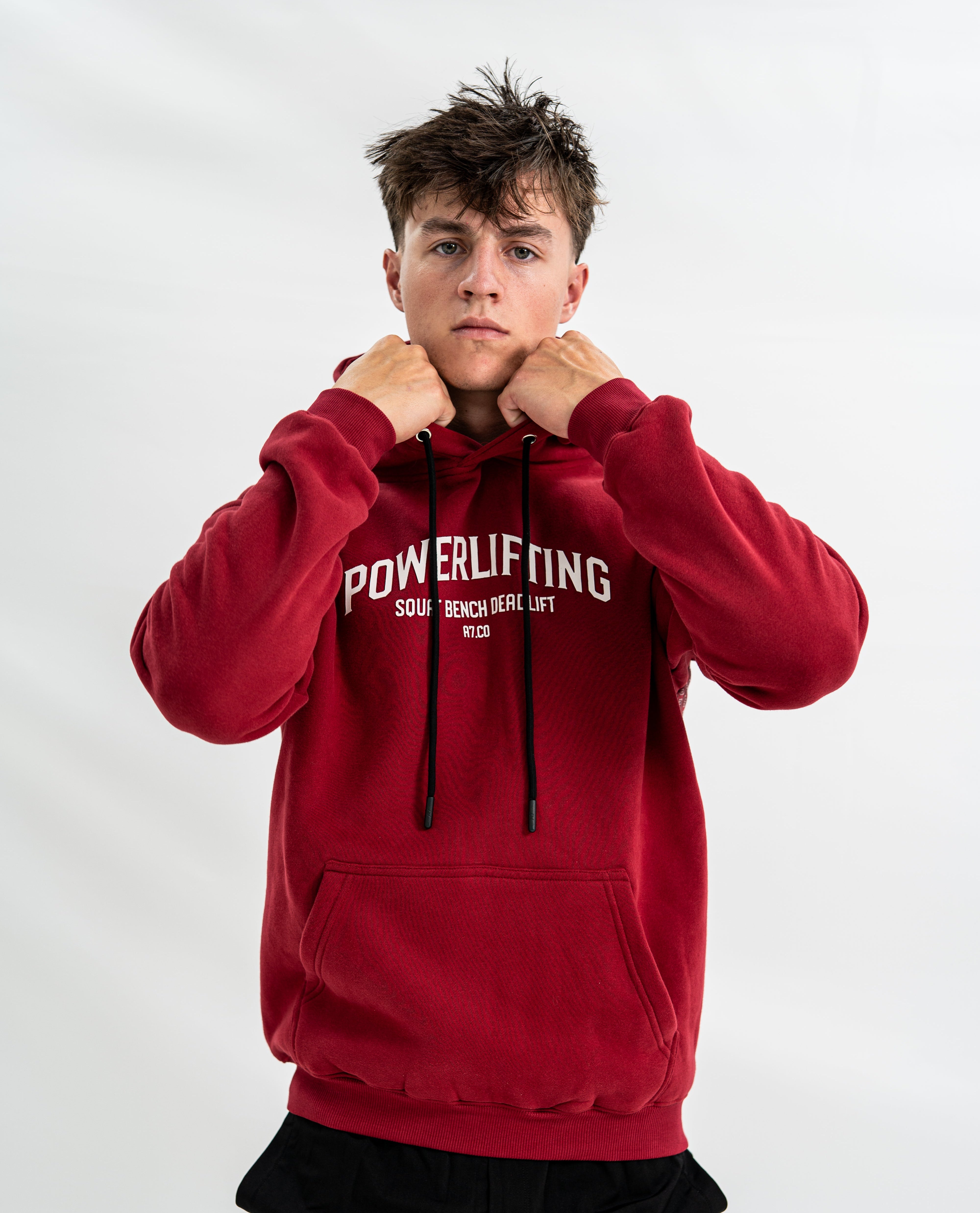 Male wearing a red 'Powerlifting' bar grip hoodie on a white background