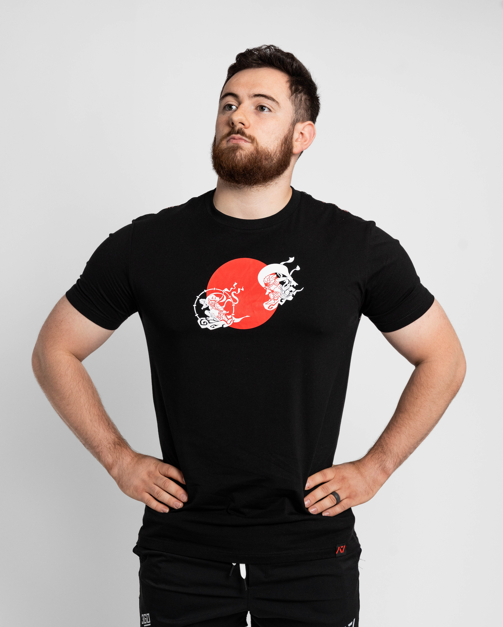 Man wearing a black t-shirt with a red and white graphic design on a light gray background