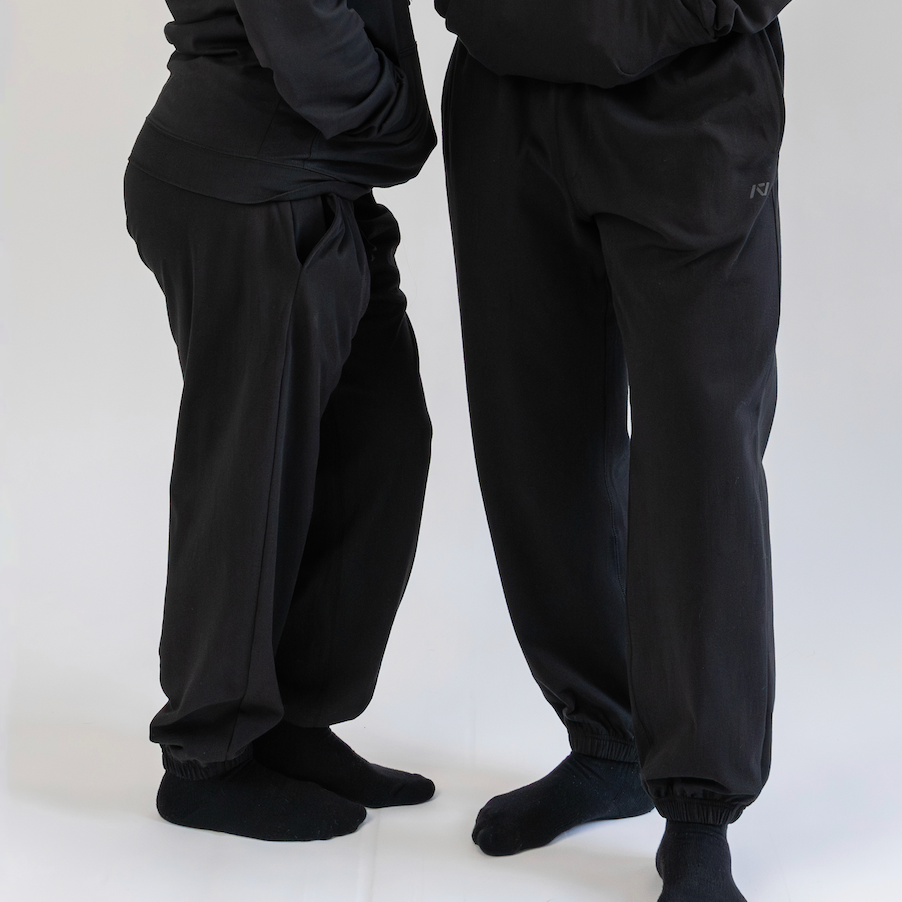 Two people wearing black pants and socks on a white background
