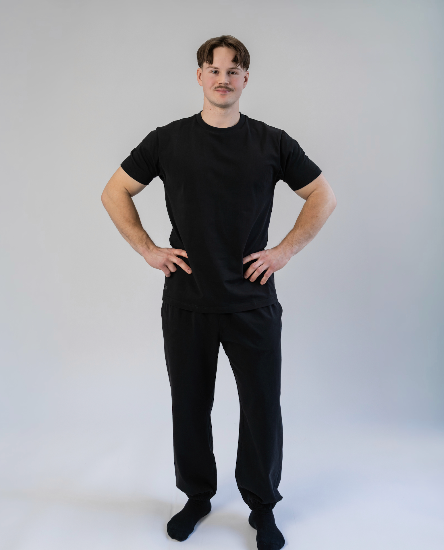 Person wearing a black t-shirt and black pants on a white background