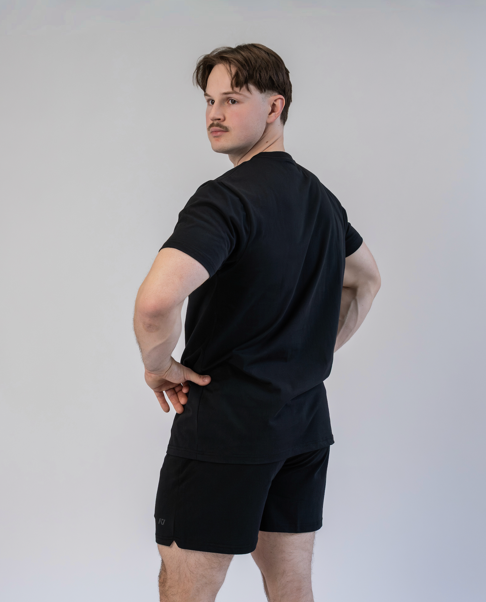 Man wearing a black t-shirt and shorts against a plain background