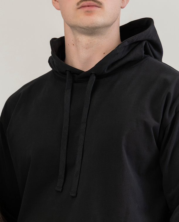 Person wearing a black hoodie against a plain background
