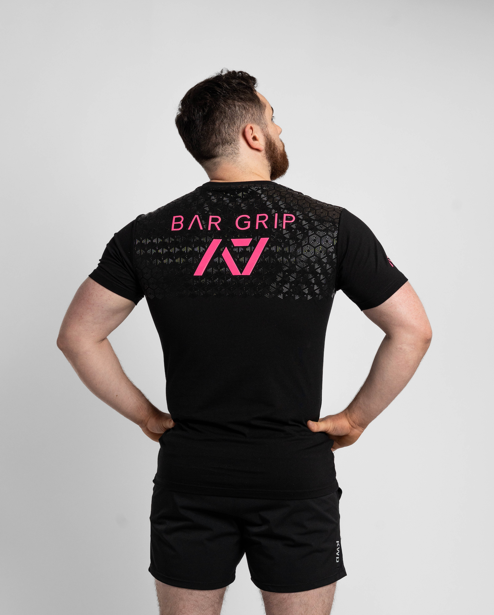 Person wearing a black t-shirt with bar grip on the back against a gray background