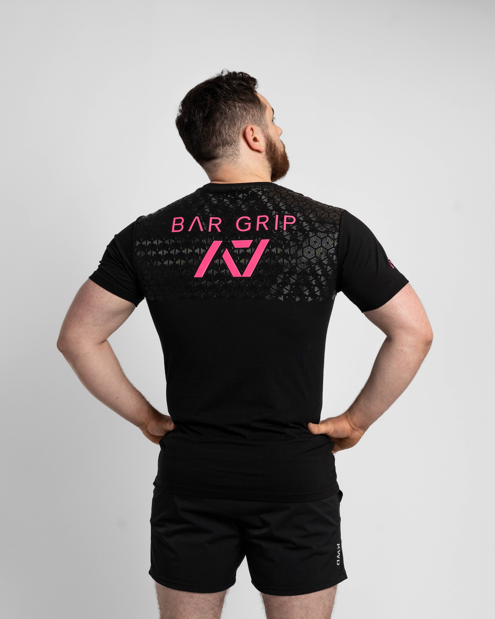 Person wearing a black t-shirt with bar grip on the back against a gray background