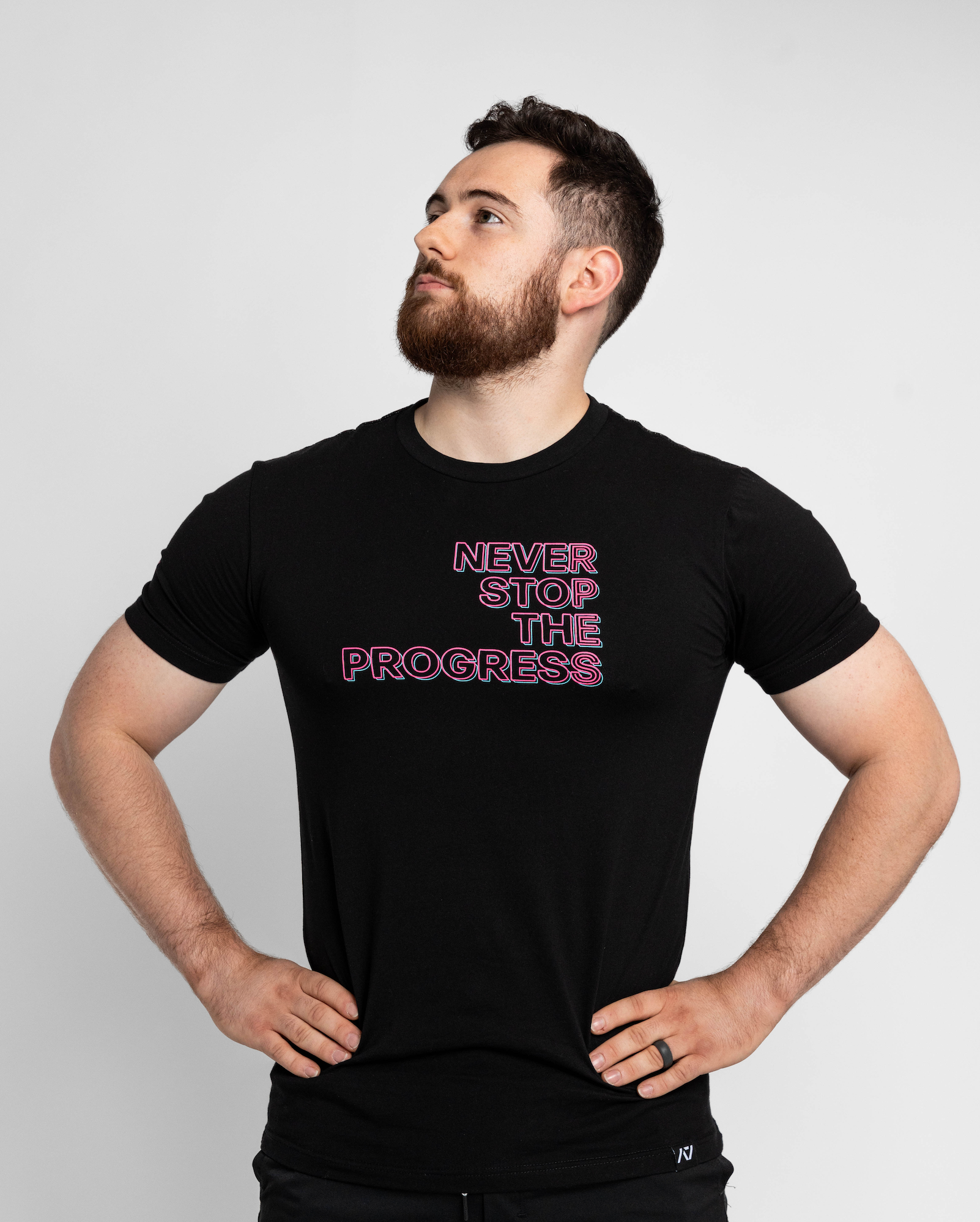 Man wearing a black t-shirt with 'Never Stop The Progress' text on a light gray background