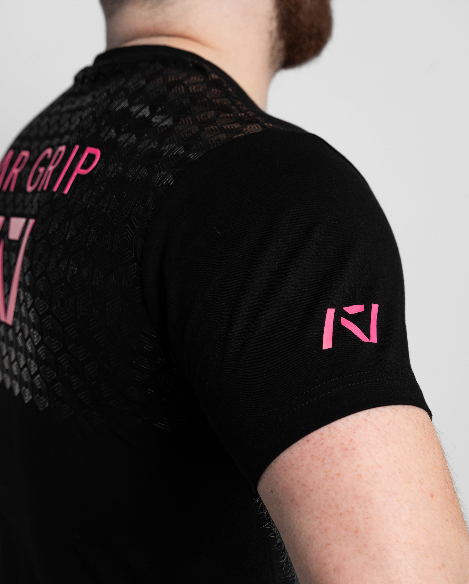 Black t-shirt with pink text and logos on a plain background