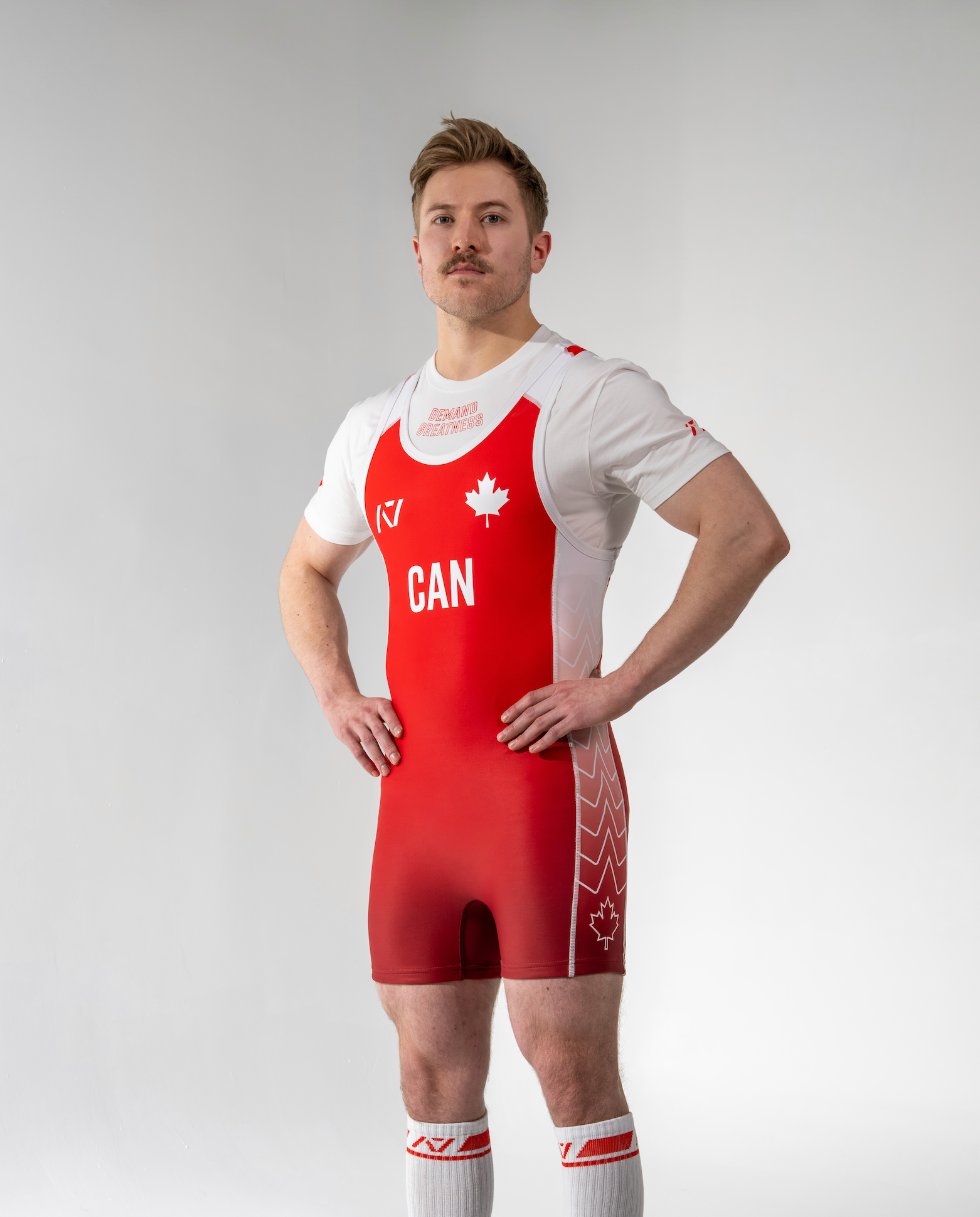 Person wearing a red and white powerlifting singlet with 'CAN' and a maple leaf on a plain background