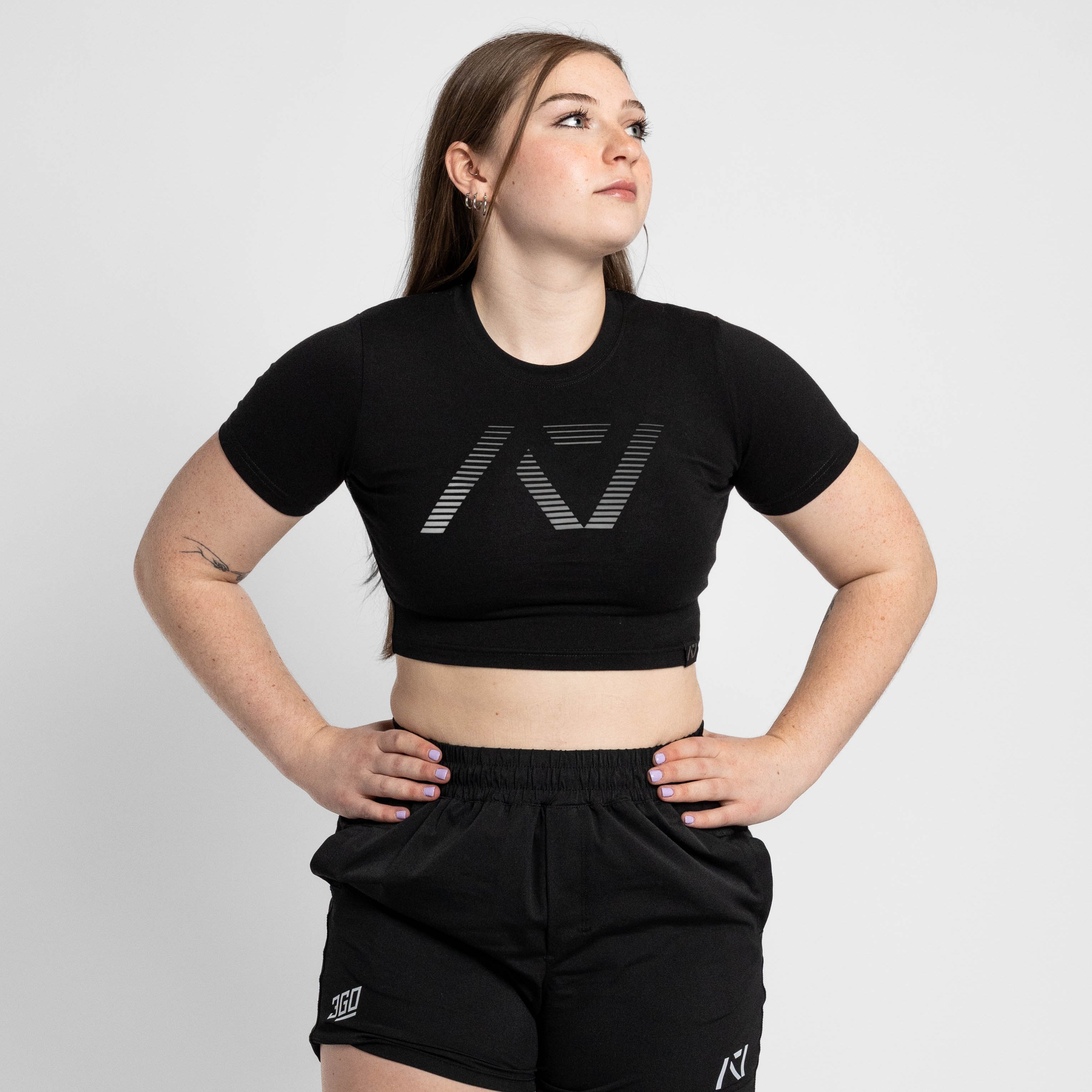 Person wearing a black crop top and shorts with a logo on a white background