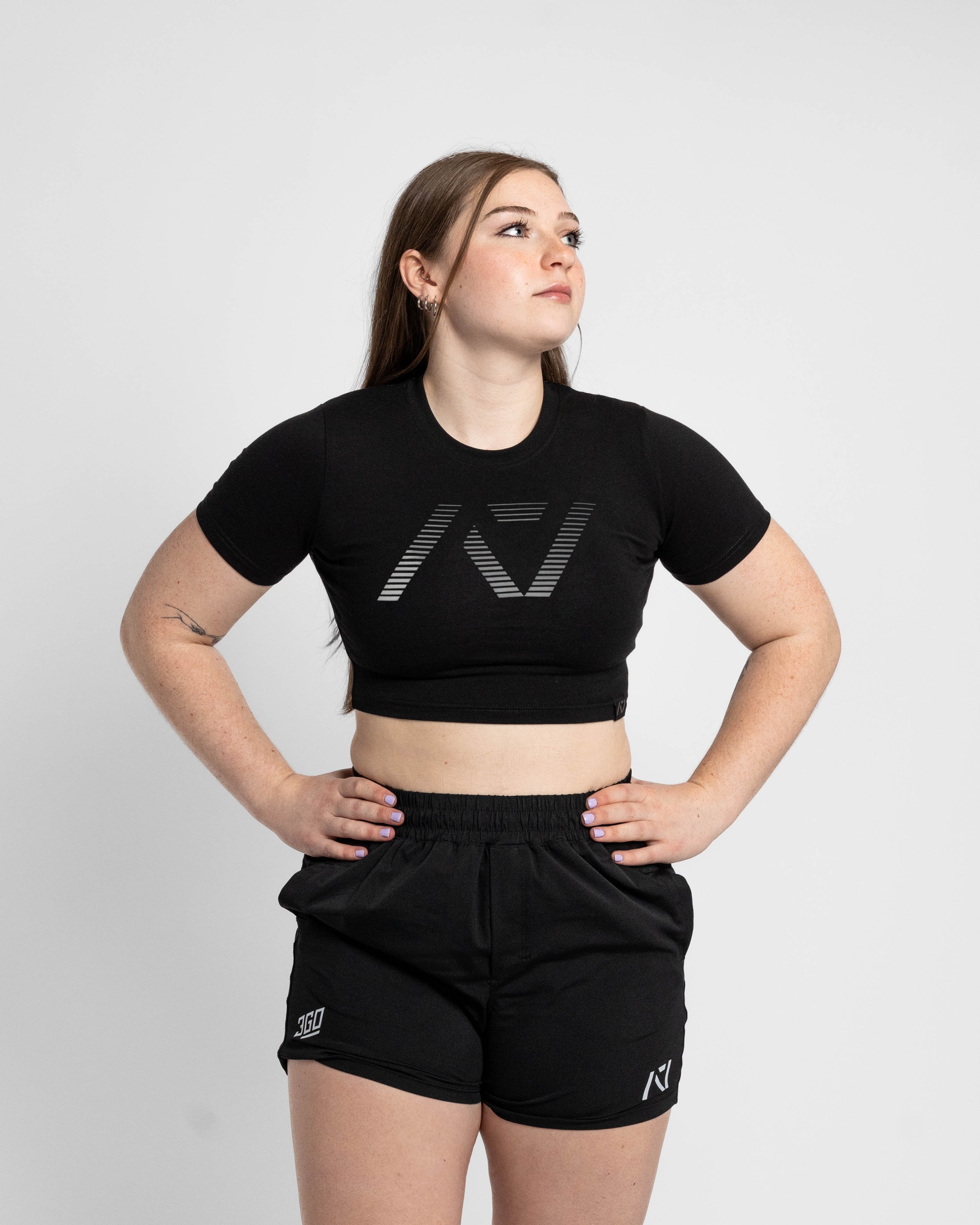 Person wearing a black crop top and shorts with a logo on a white background