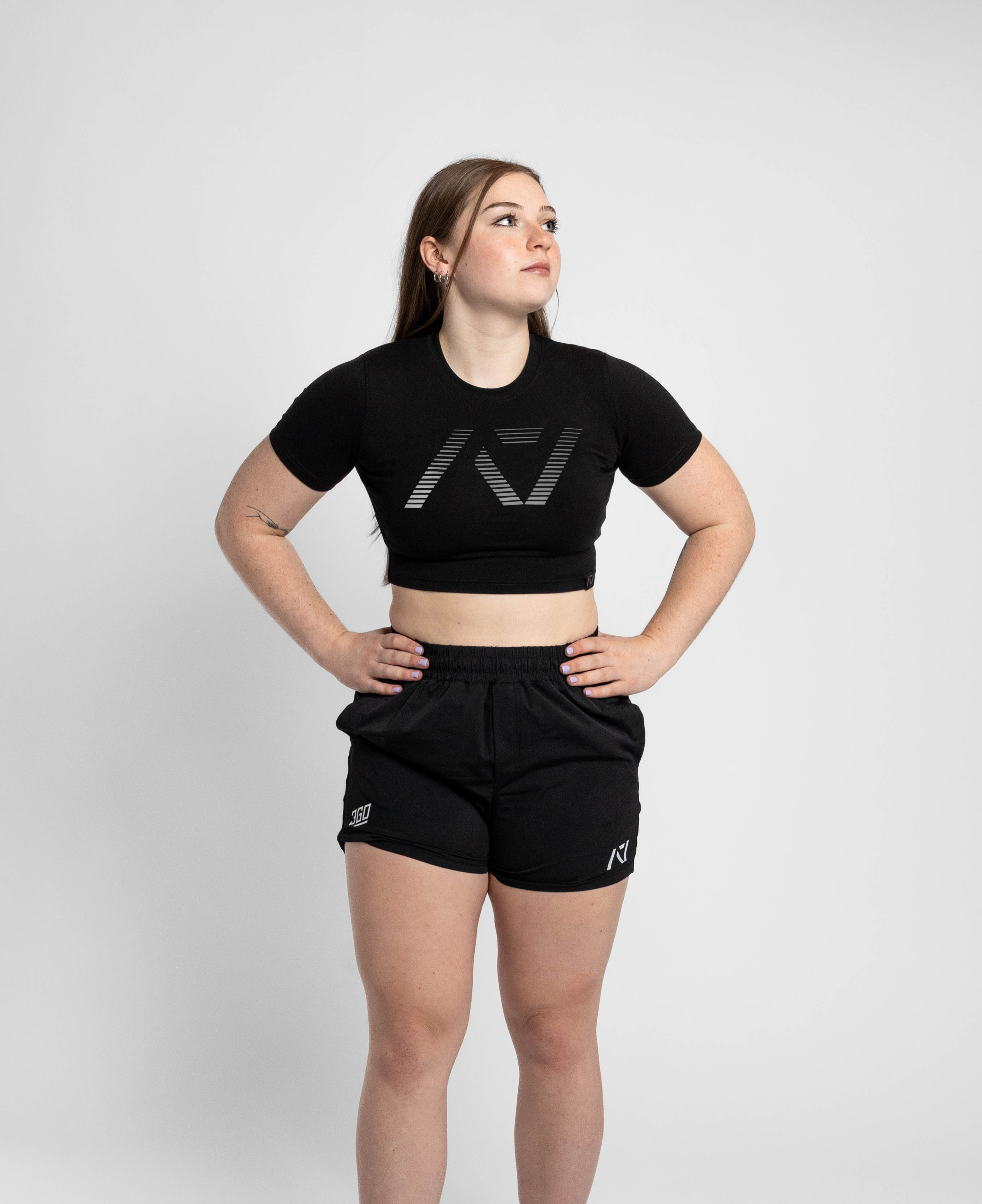 Woman wearing a black crop top and shorts with a logo on a white background