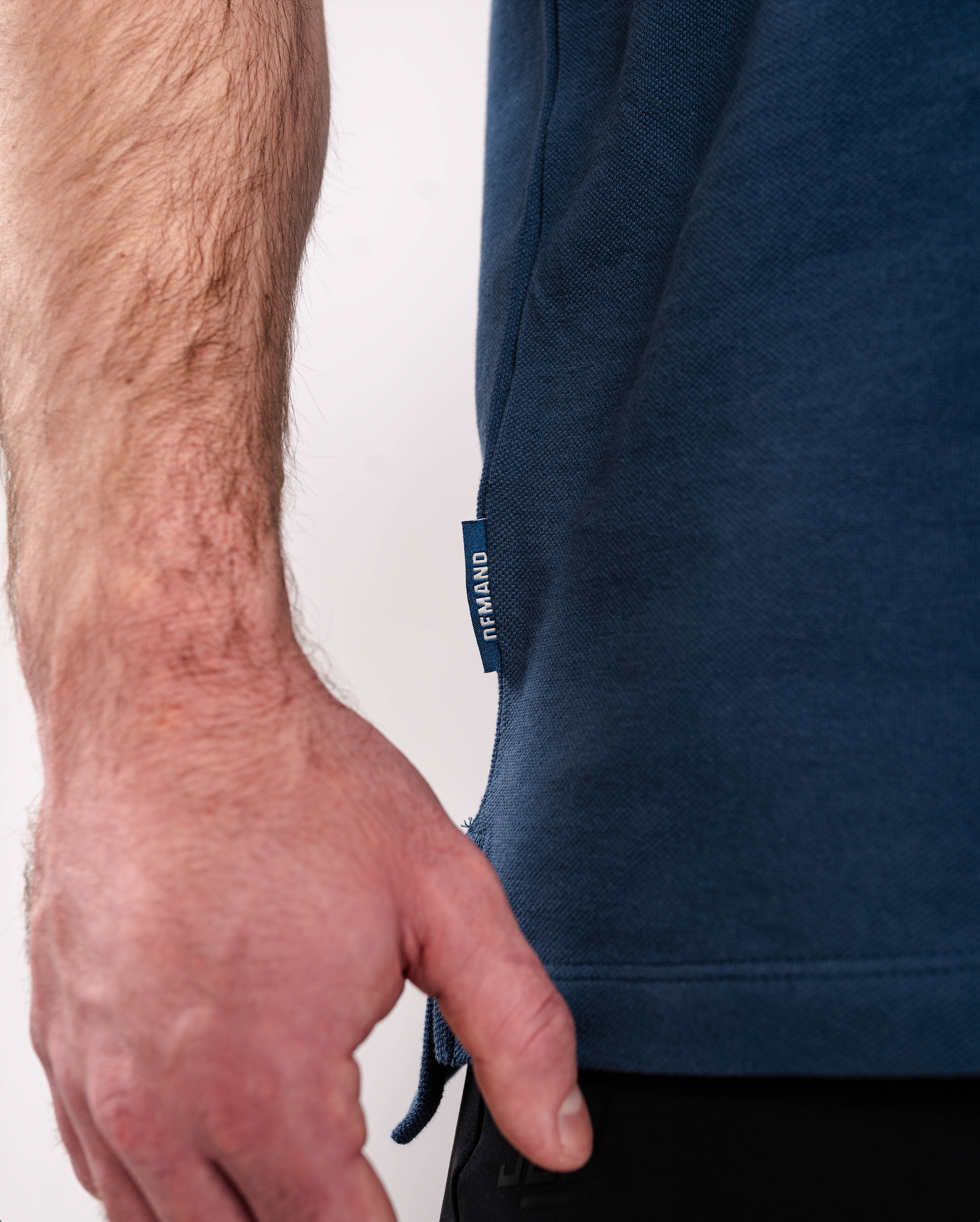 Close-up of the woven A7 hem tag on the Cotton Polo – Tides, stitched at the bottom hem for a subtle branded detail.