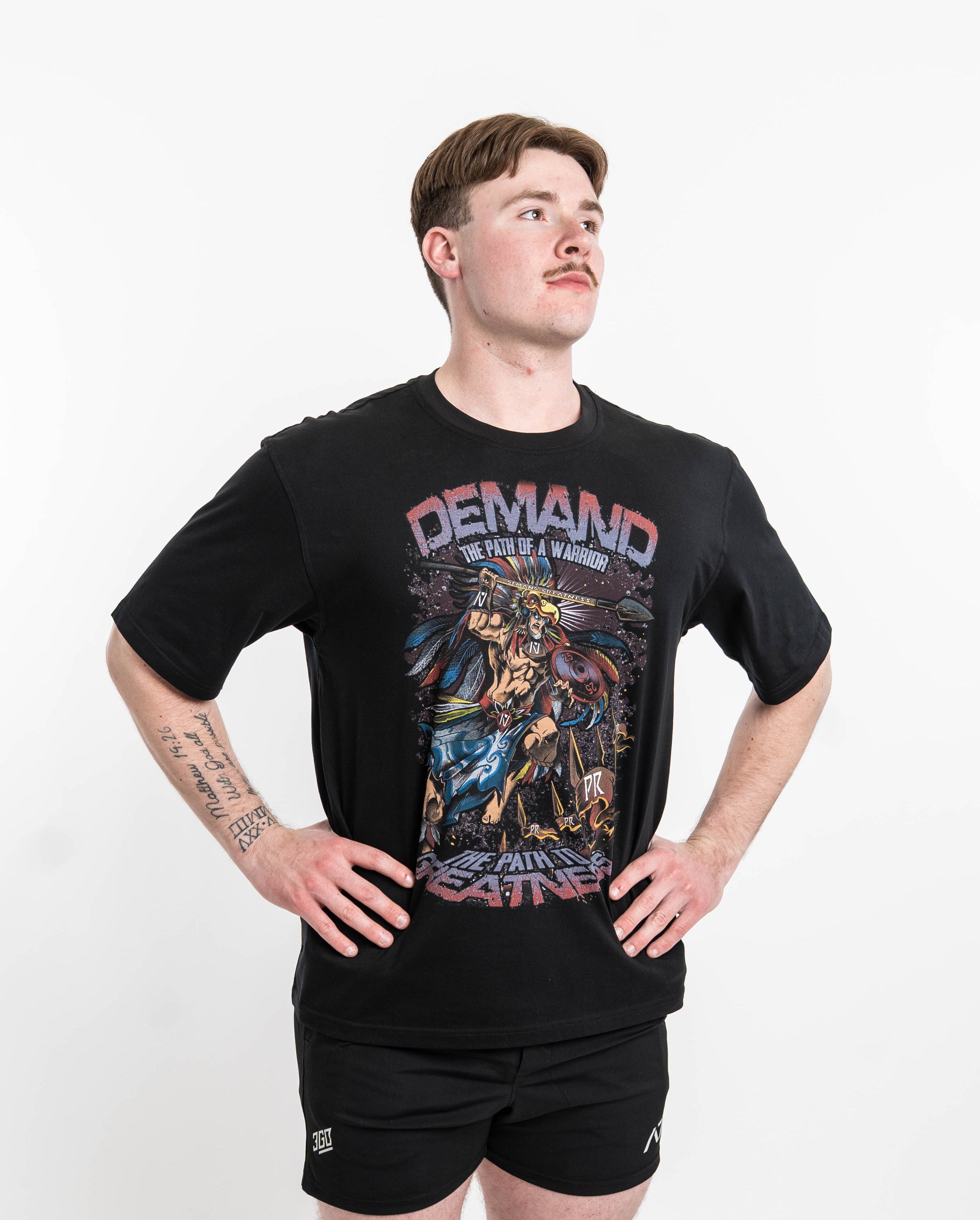 ront view of Aztec Warrior Over-Fit Unisex Shirt showcasing the detailed Aztec warrior design with eagle headdress and "Demand Greatness" spear.