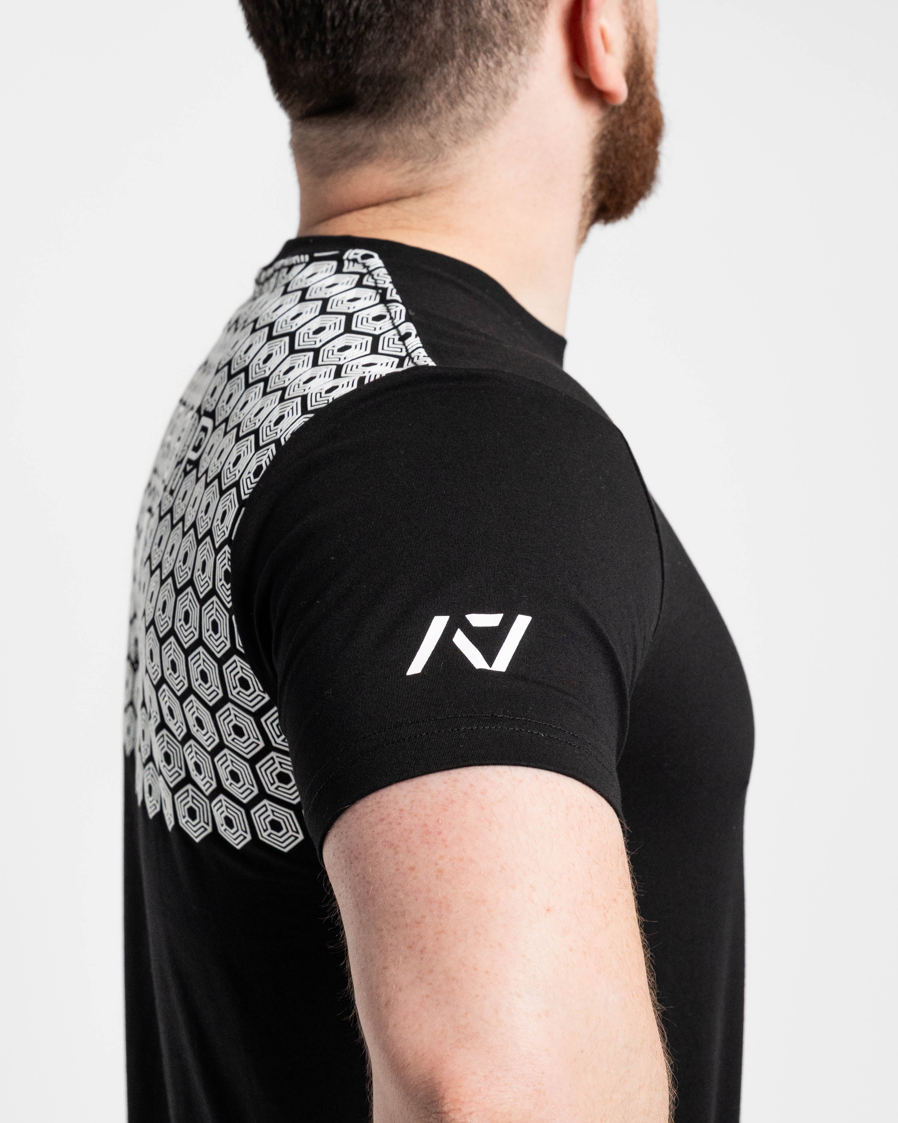 Black athletic shirt with bar grip and sleeve and brand logo, worn by a person.