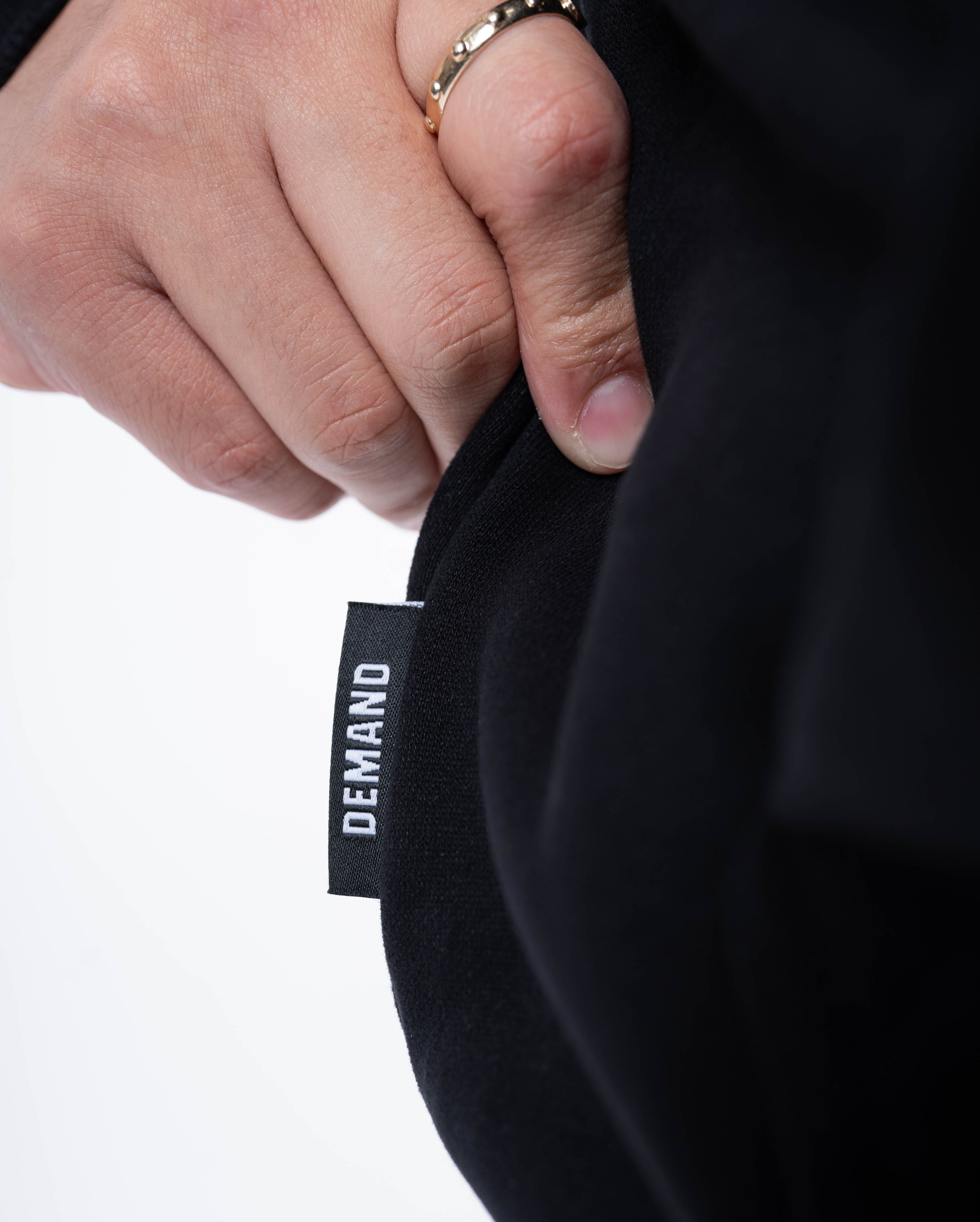 Close-up of the A7 hem tag stitched on the side seam of the Built By Hoodie – Black, highlighting premium branding and construction detail.