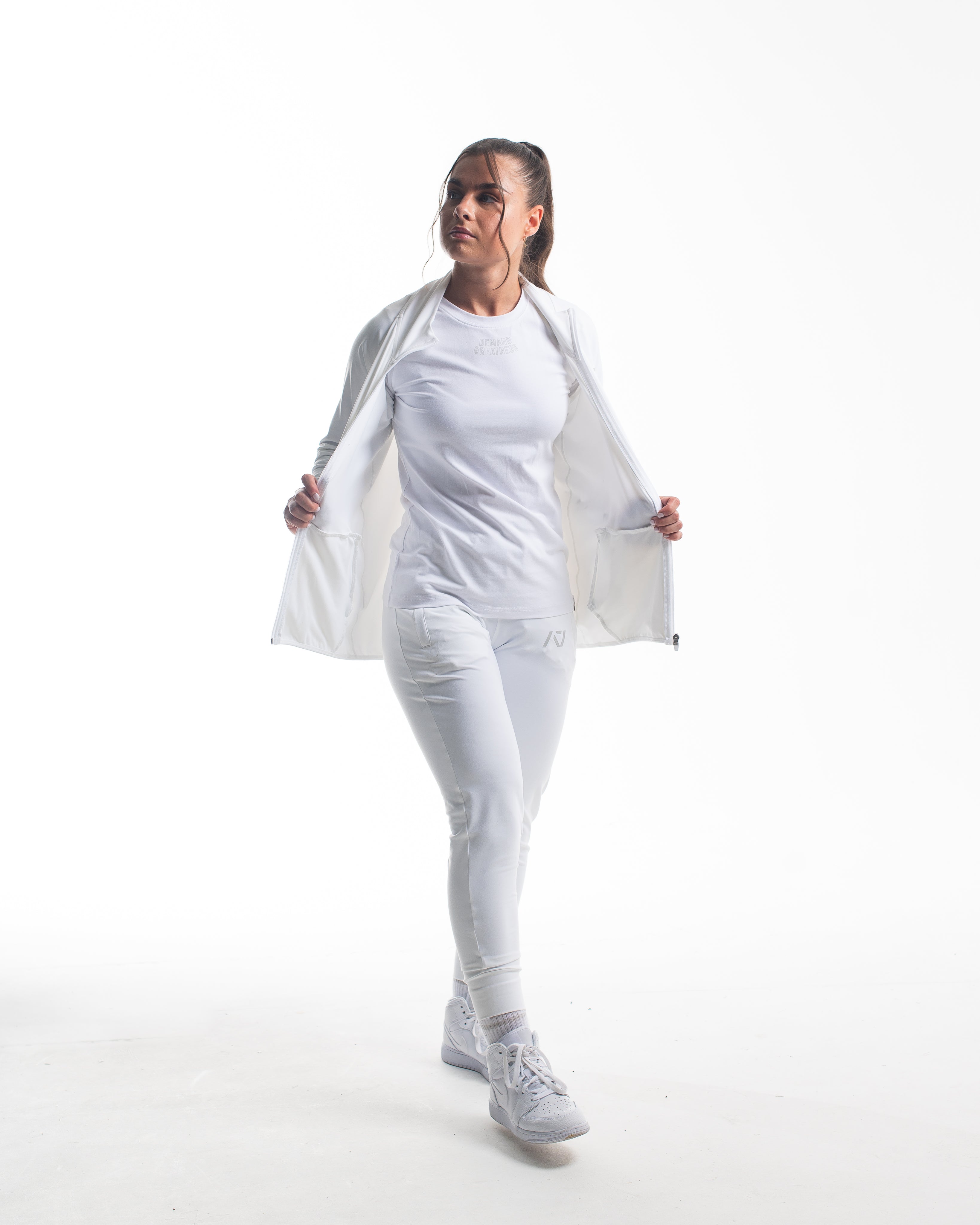 Full body view of athlete wearing the Defy Jacket – Polar, highlighting the tapered unisex fit, full zip design, and clean silhouette paired with matching joggers.