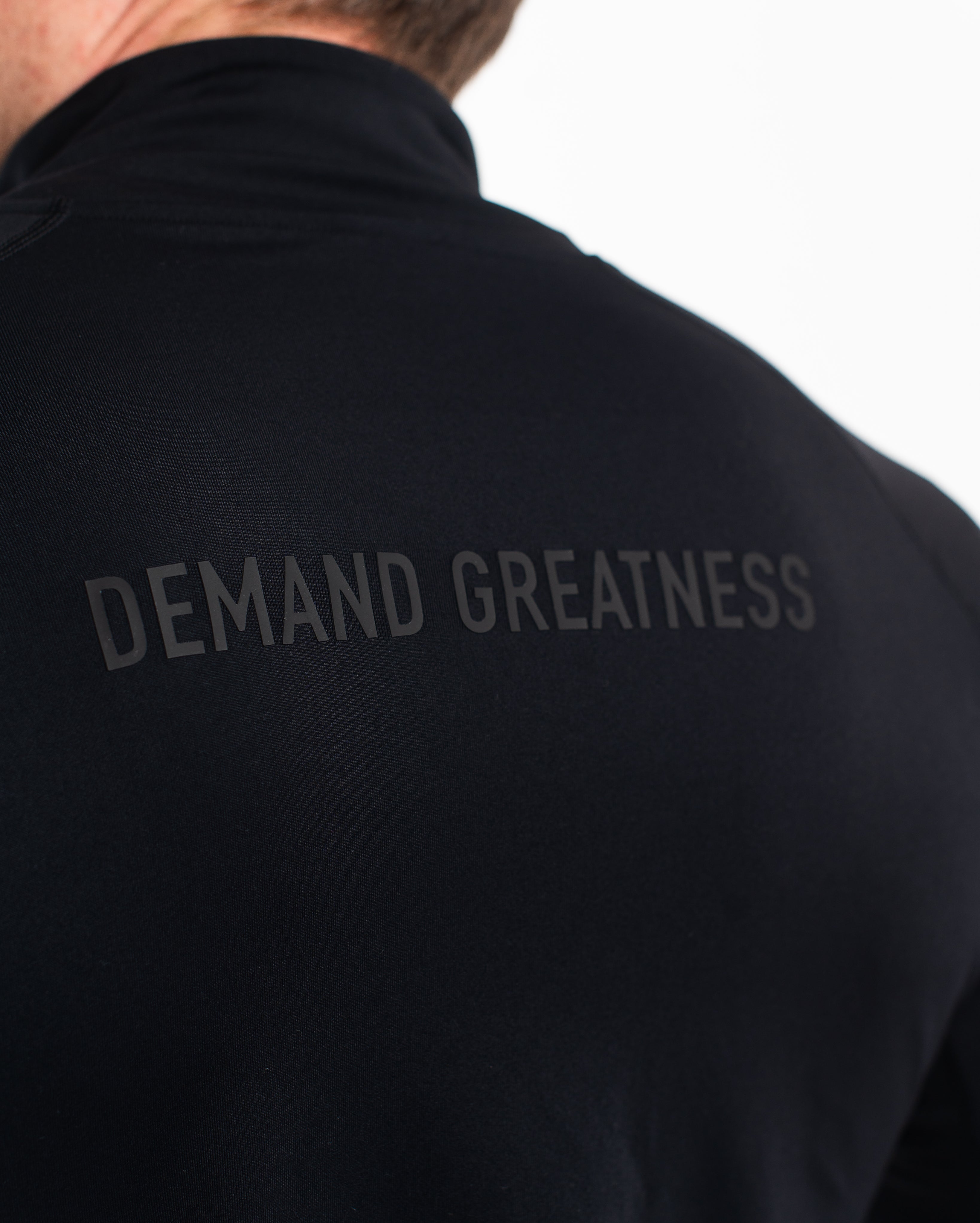 Back view of A7 Defy Jacket – Stealth, featuring the 3D “Demand Greatness” silicone graphic.