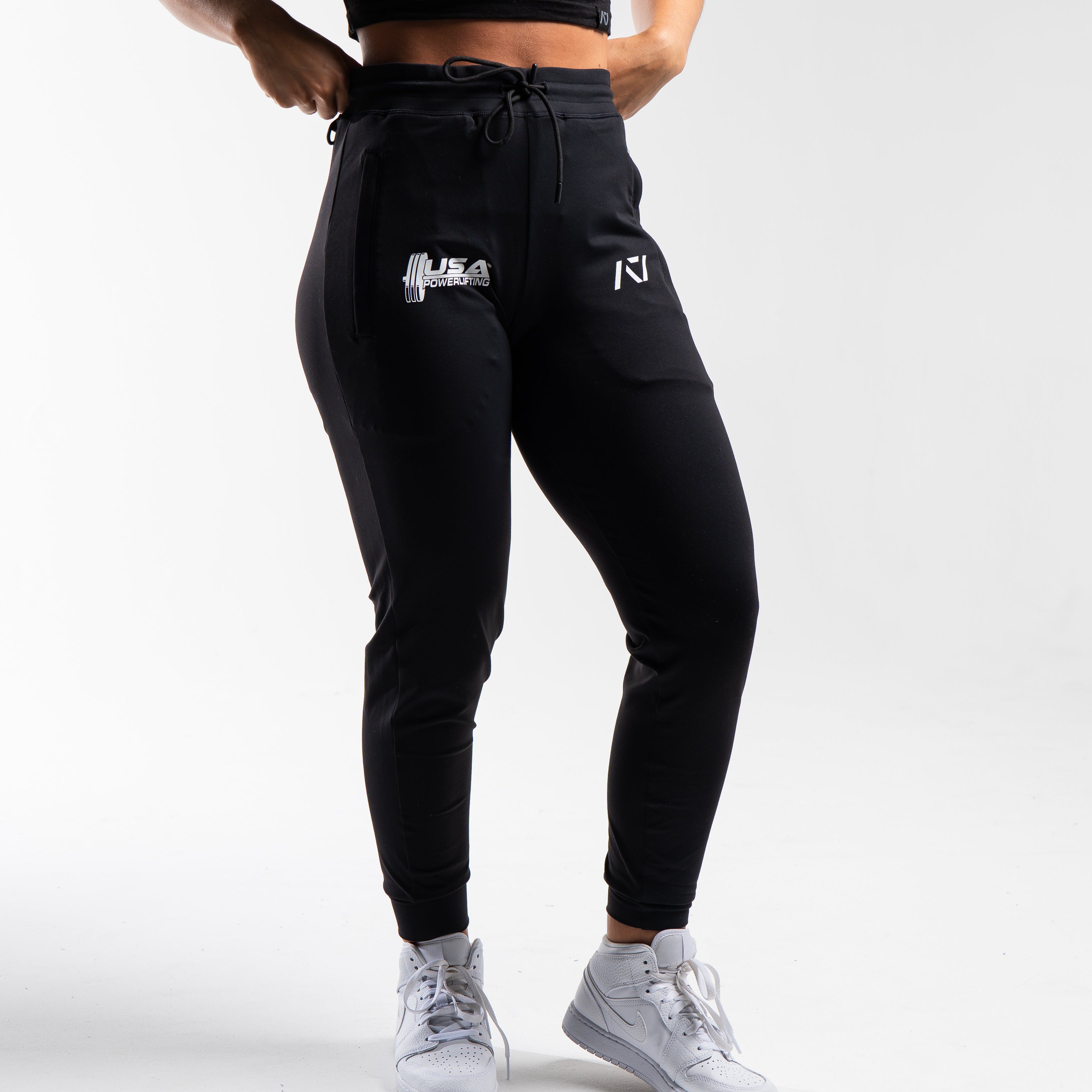 Front view of the USAPL Classic Defy Joggers showing zippered pockets, mid-rise waist, and logos.