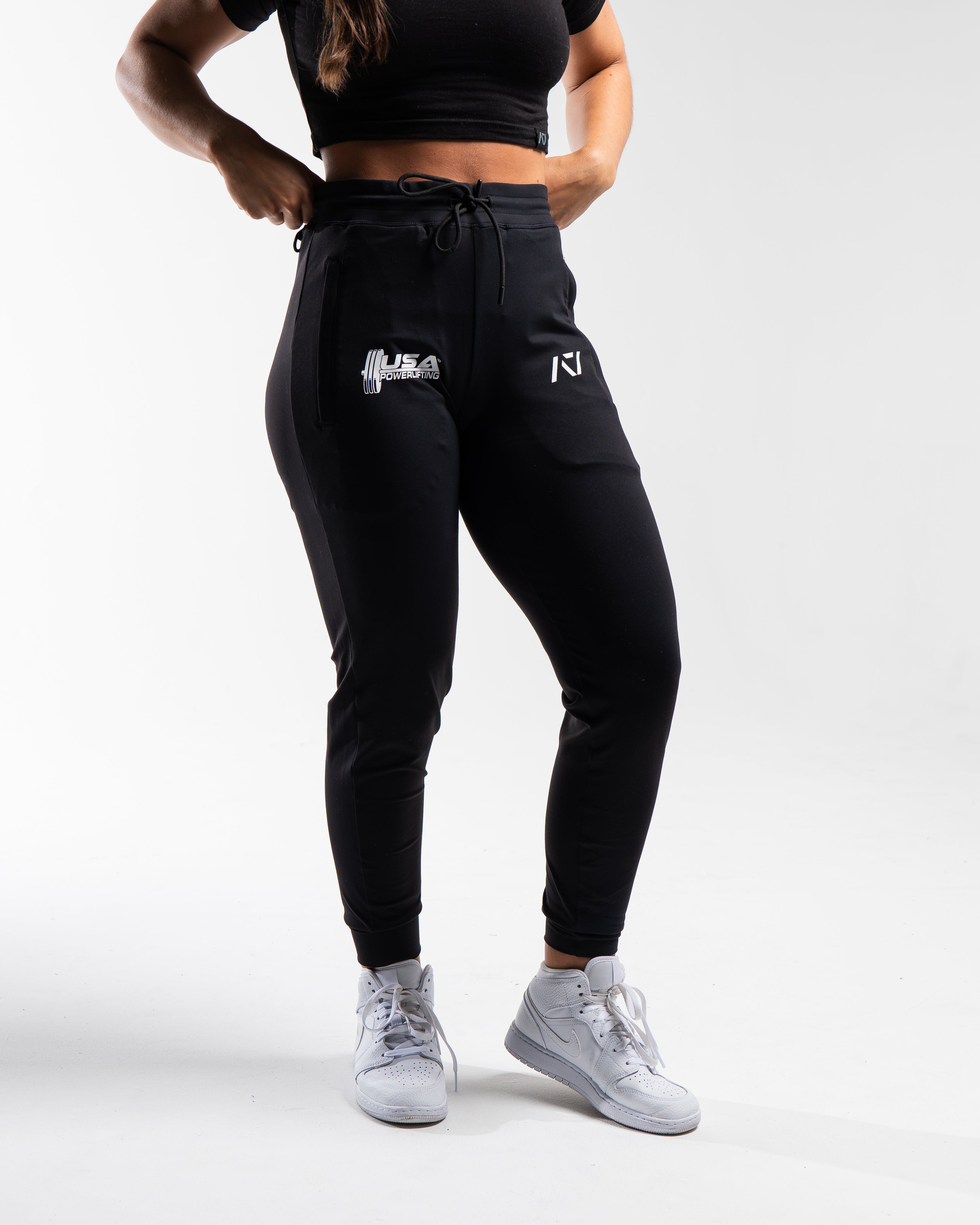 Front view of the USAPL Classic Defy Joggers showing zippered pockets, mid-rise waist, and logos.