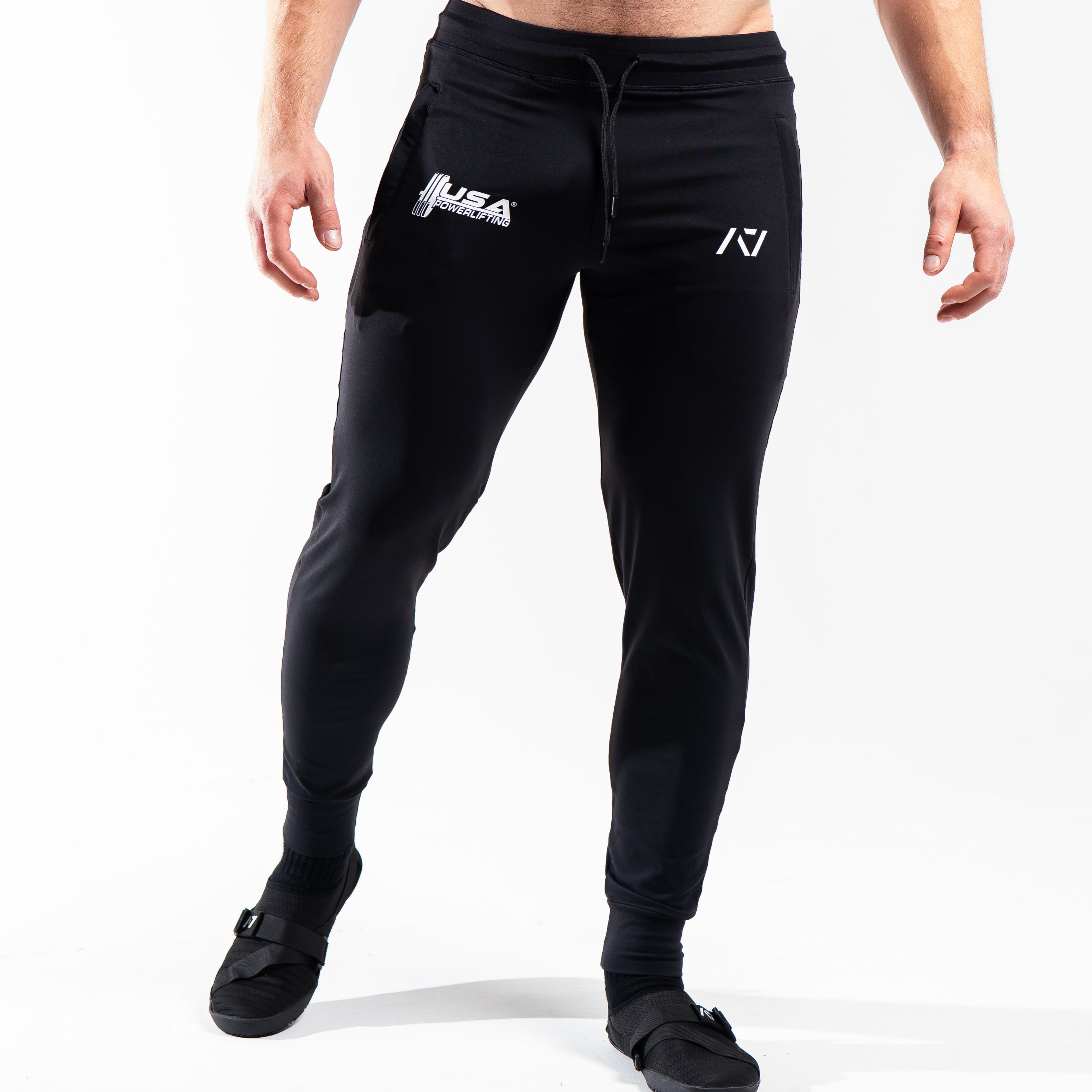 Front view of the USAPL Classic Defy Joggers showing zippered pockets, mid-rise waist, and logos.