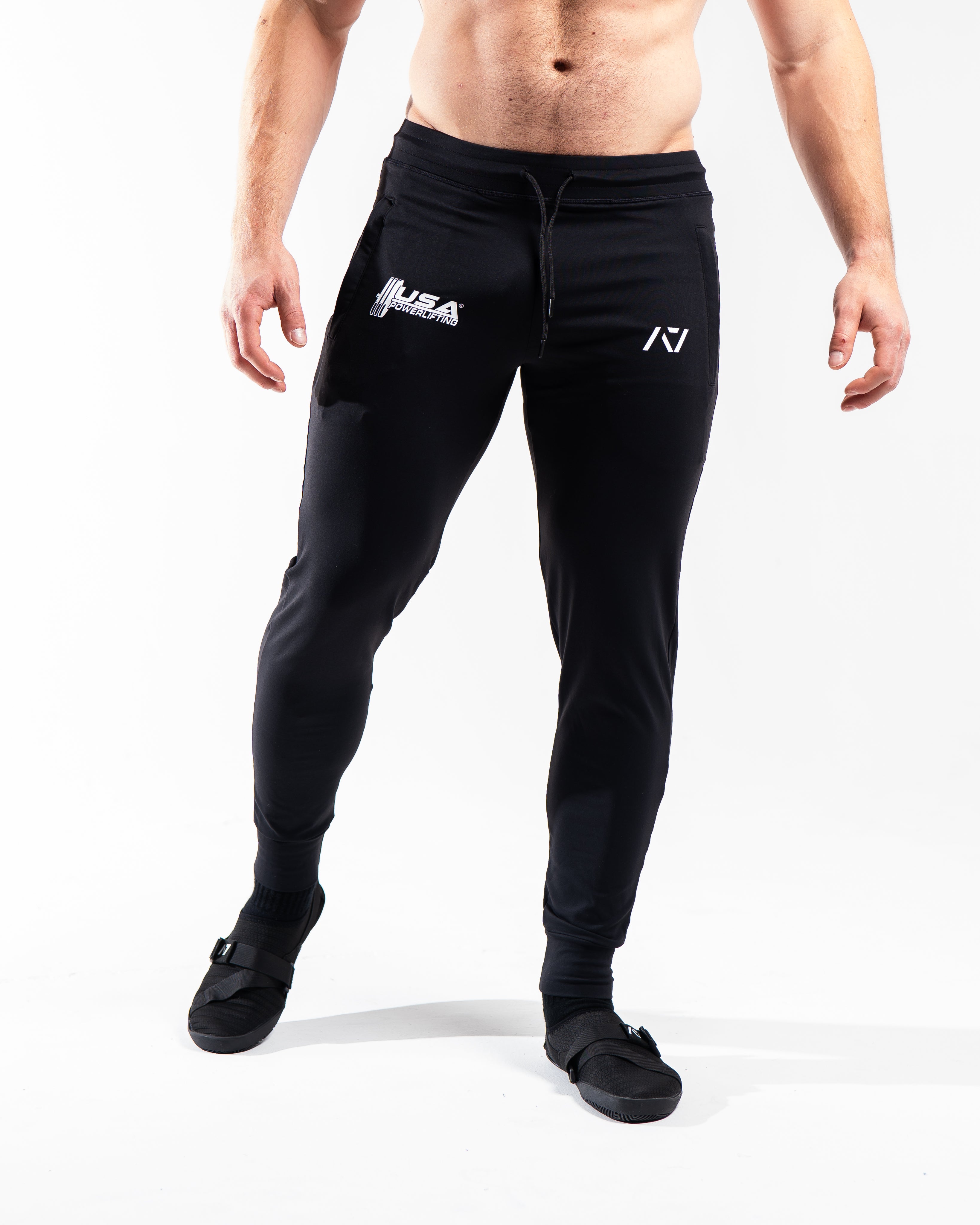 Front view of the USAPL Classic Defy Joggers showing zippered pockets, mid-rise waist, and logos.