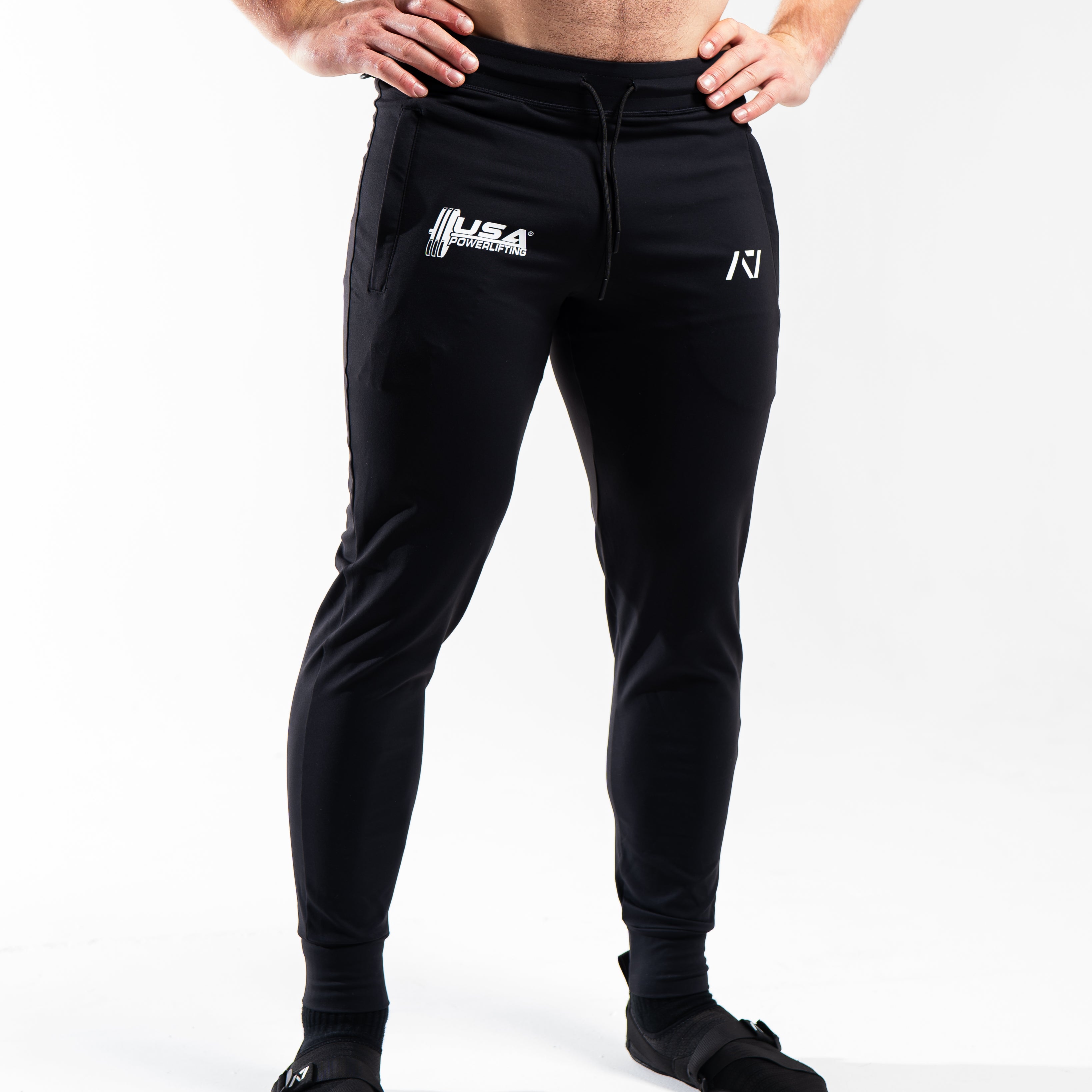 Front view of the USAPL Classic Defy Joggers showing zippered pockets, mid-rise waist, and logos.