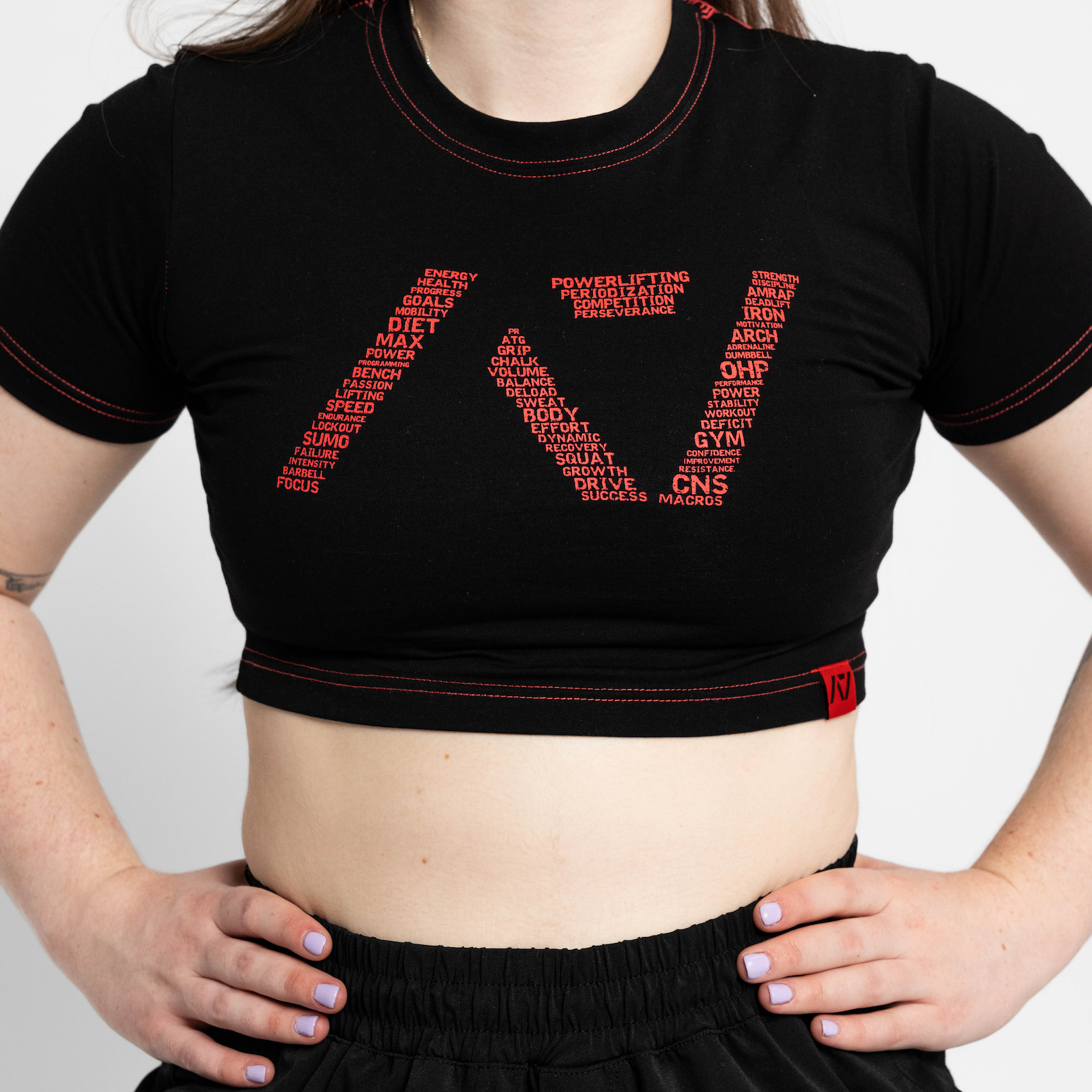 Person wearing a black crop top with red text design on a plain background