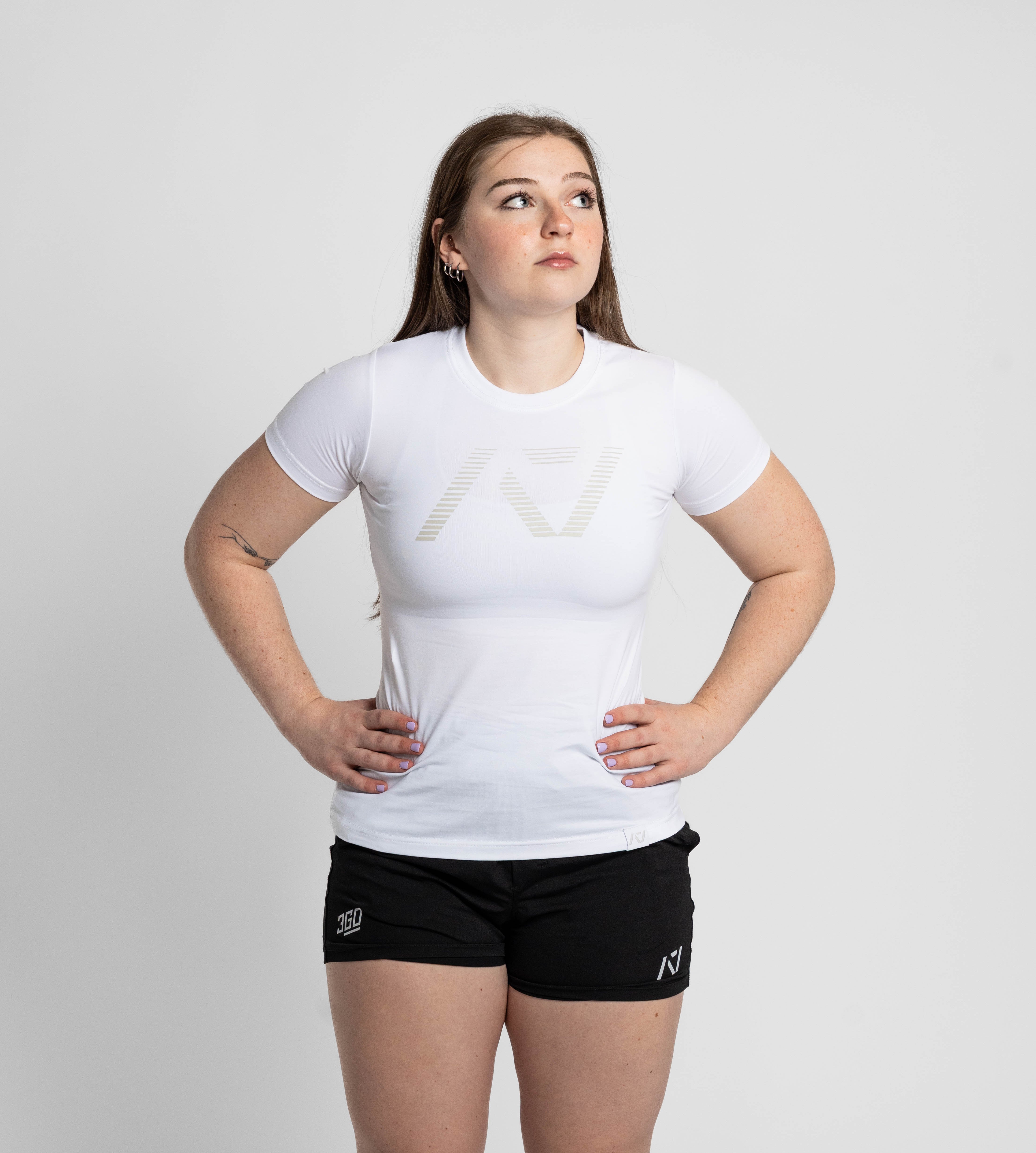 Person wearing a white t-shirt and black shorts with a logo on a plain background