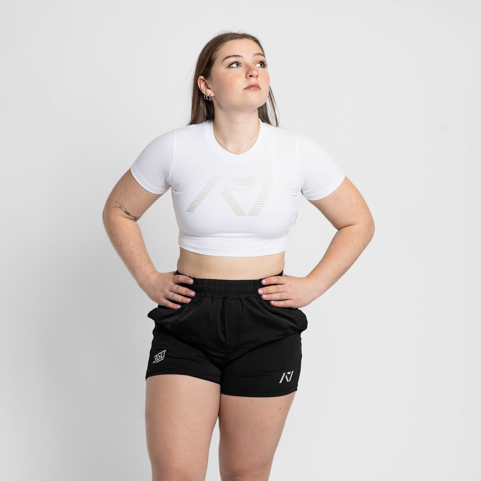 Person wearing a white crop top and black shorts on a plain background