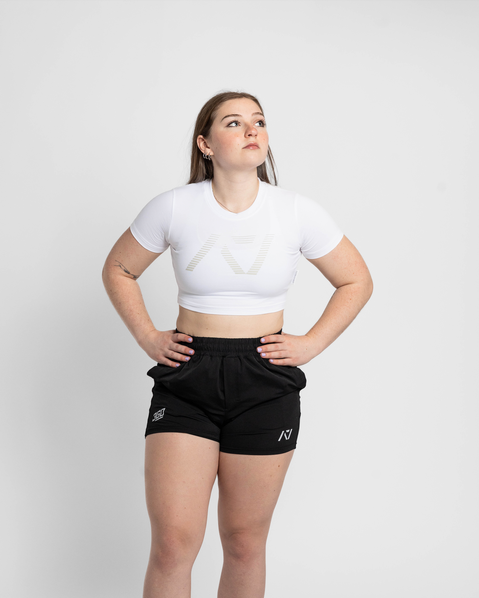 Person wearing a white crop top and black shorts on a plain background