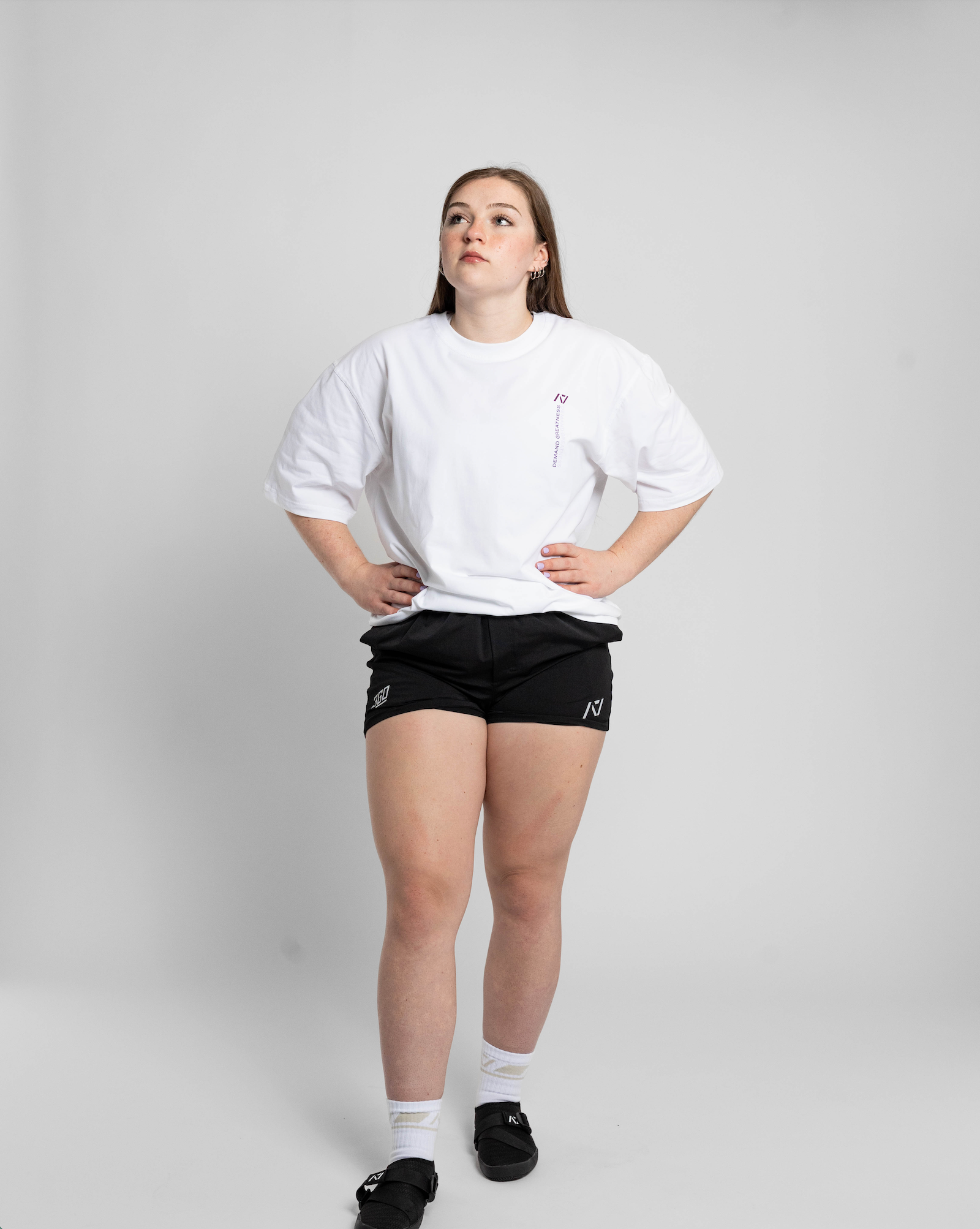 Person wearing a white oversized t-shirt and black shorts on a plain background