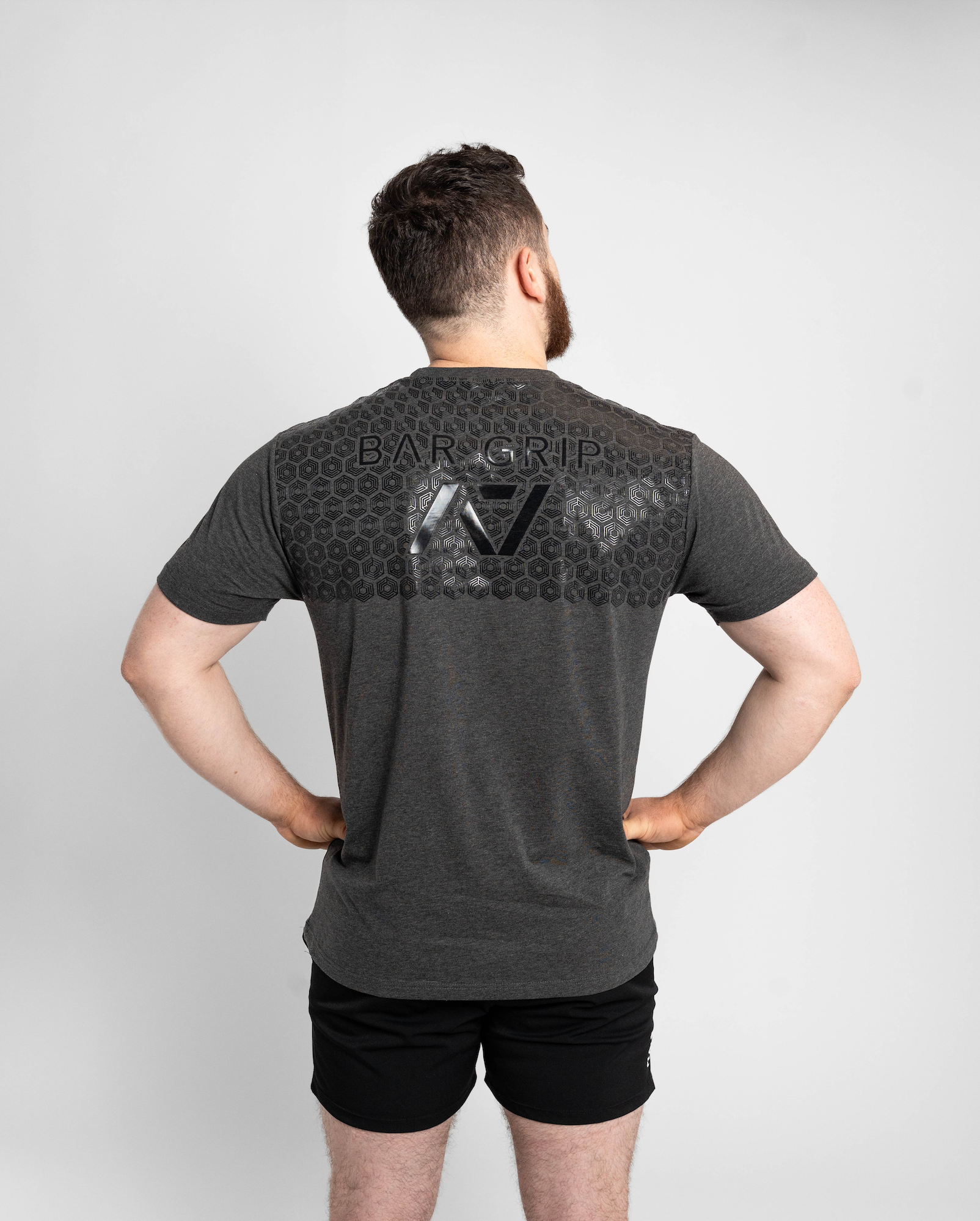 Man wearing a gray t-shirt with a7 bar grip on the back against a white background