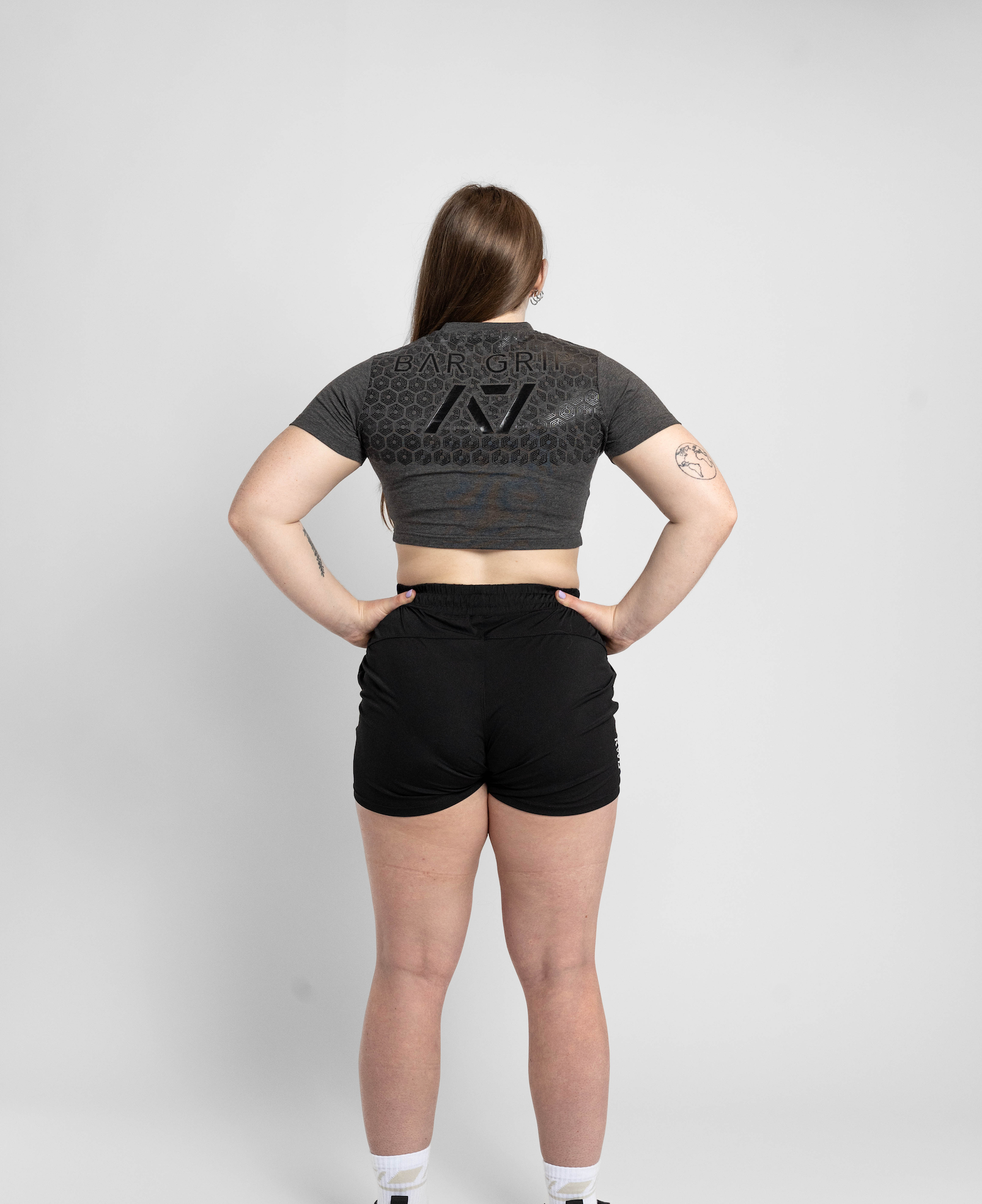 Person wearing a dark gray crop top and black shorts on a light gray background