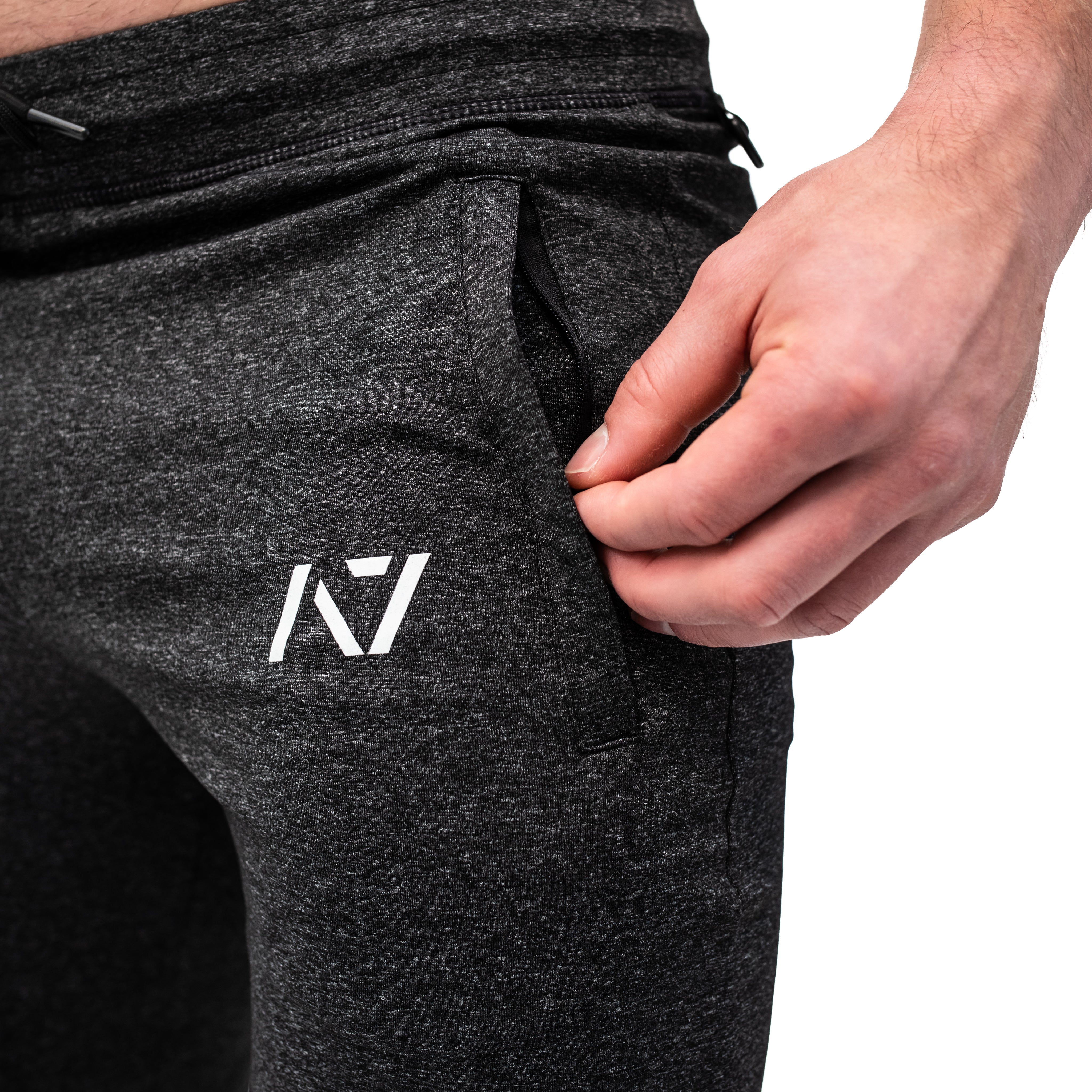 Close-up of the zippered front pocket on the Charcoal Defy Joggers, highlighting the matte zipper pull and stretch-knit fabric for secure and flexible storage.
