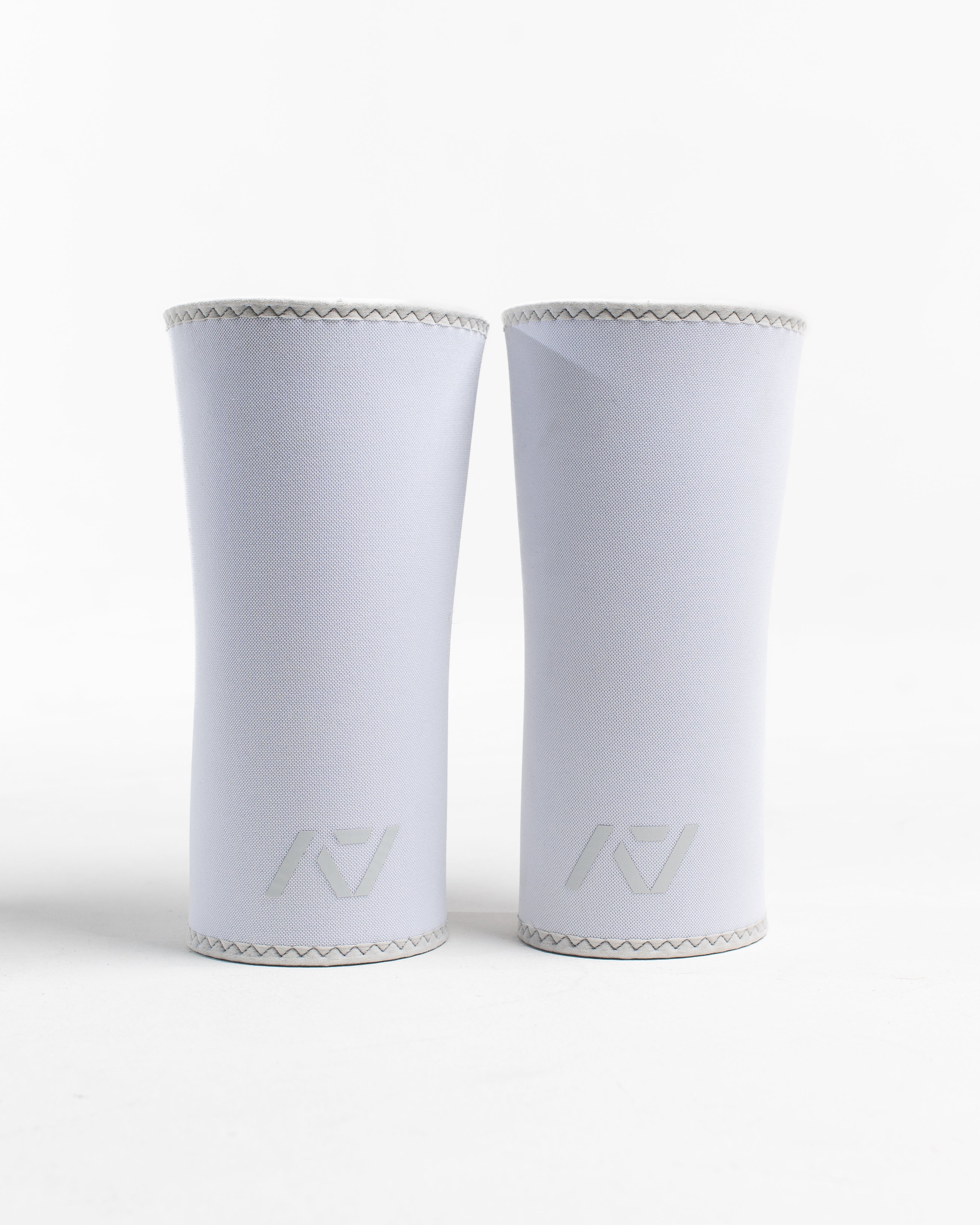 A pair of white neoprene knee sleeves with an hourglass-shaped center fit, displayed against a white background.