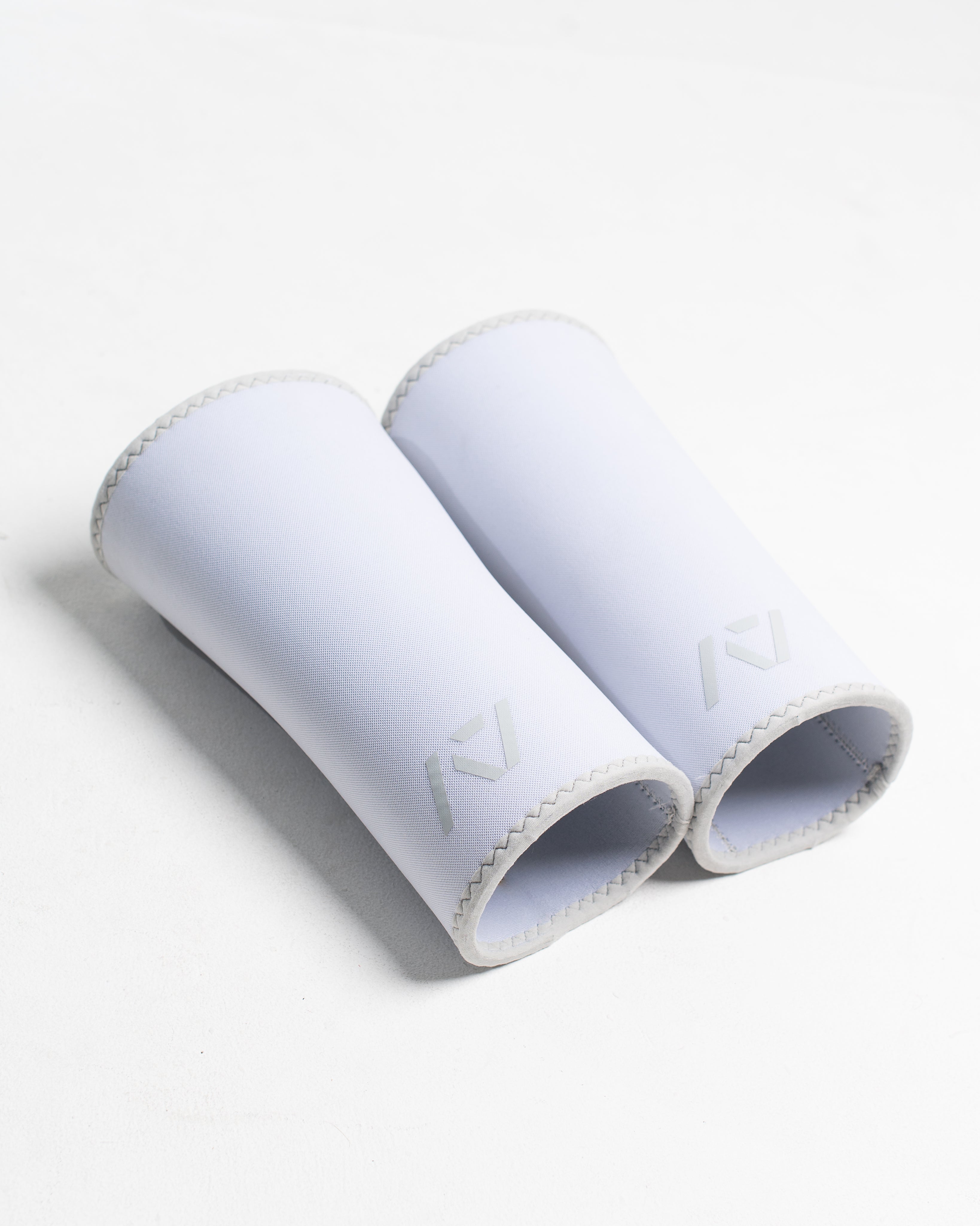Pair of white hourglass knee sleeves on a white background
